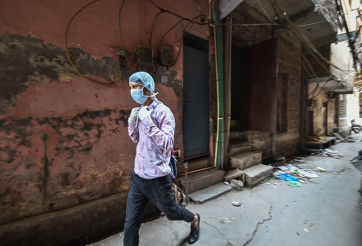 Chand Mohammad wearing a face mask and gloves leaves from his house for work, at Seelampur. Credit: PTI Photo