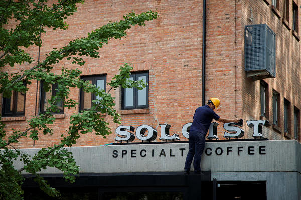 A worker cleans the sign at a cafe of the local coffee house chain Soloist Coffee in Beijing, China. Credit: Reuters