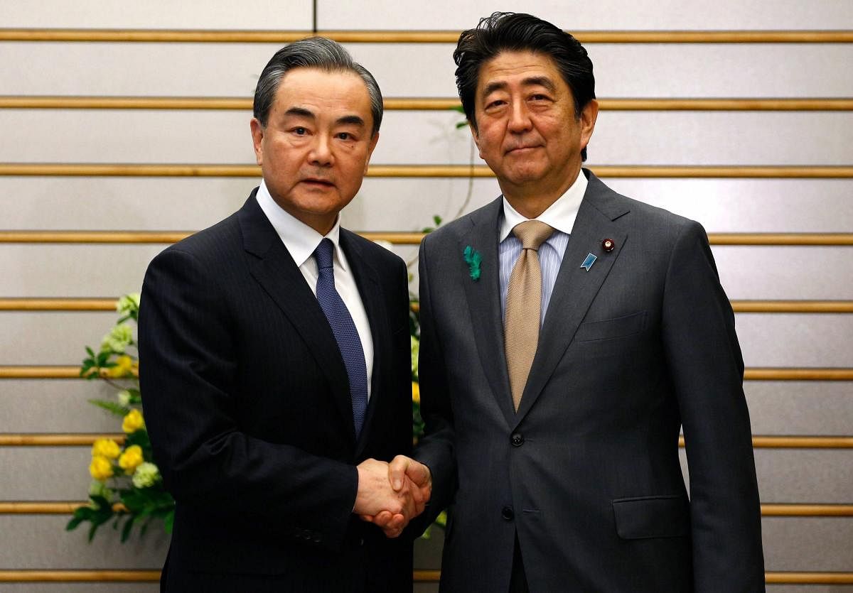 Chinese Foreign Minister Wang Yi, left, poses with Japanese Prime Minister Shinzo Abe for a photo prior to their meeting at Abe's official residence in Tokyo Monday, April 16, 2018. China and Japan resumed high-level economic talks Monday after a hiatus of nearly eight years in a sign of improving ties in their often-frosty relationship. AP/PTI