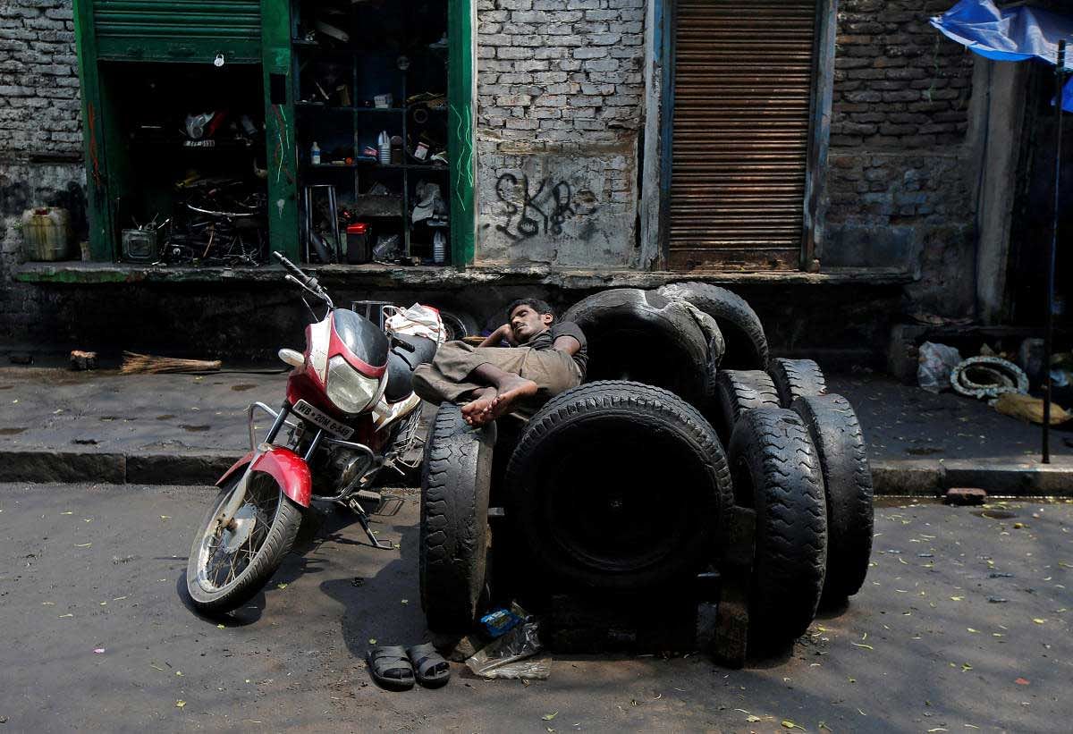 A worker rests on used tyres in front of an automobile repair shop in Kolkata, India. Reuters Photo
