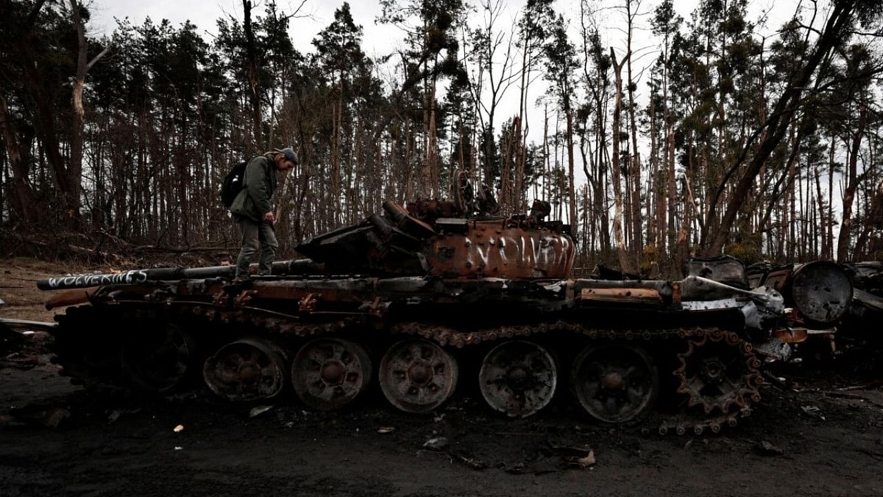 <div class="paragraphs"><p>A man stands on the top of a destroyed Russian tank, amid Russia's Invasion of Ukraine near Buzova. </p></div>