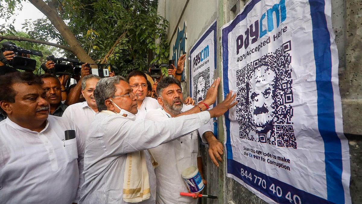 <div class="paragraphs"><p>File photo of D K Shivakumar, Siddaramaiah pasting a poster with QR code and 'PayCM' written above targetting the then-Karnataka CM Basavaraj Bommai, during a protest  in Bengaluru.</p></div>