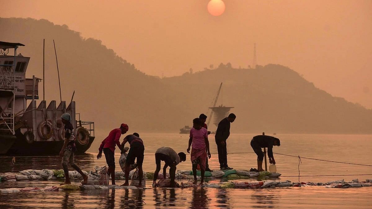 <div class="paragraphs"><p>Workers put sacks of sand at the bank of River Brahmaputra to make a pavement during sunset, in Guwahati.</p></div>