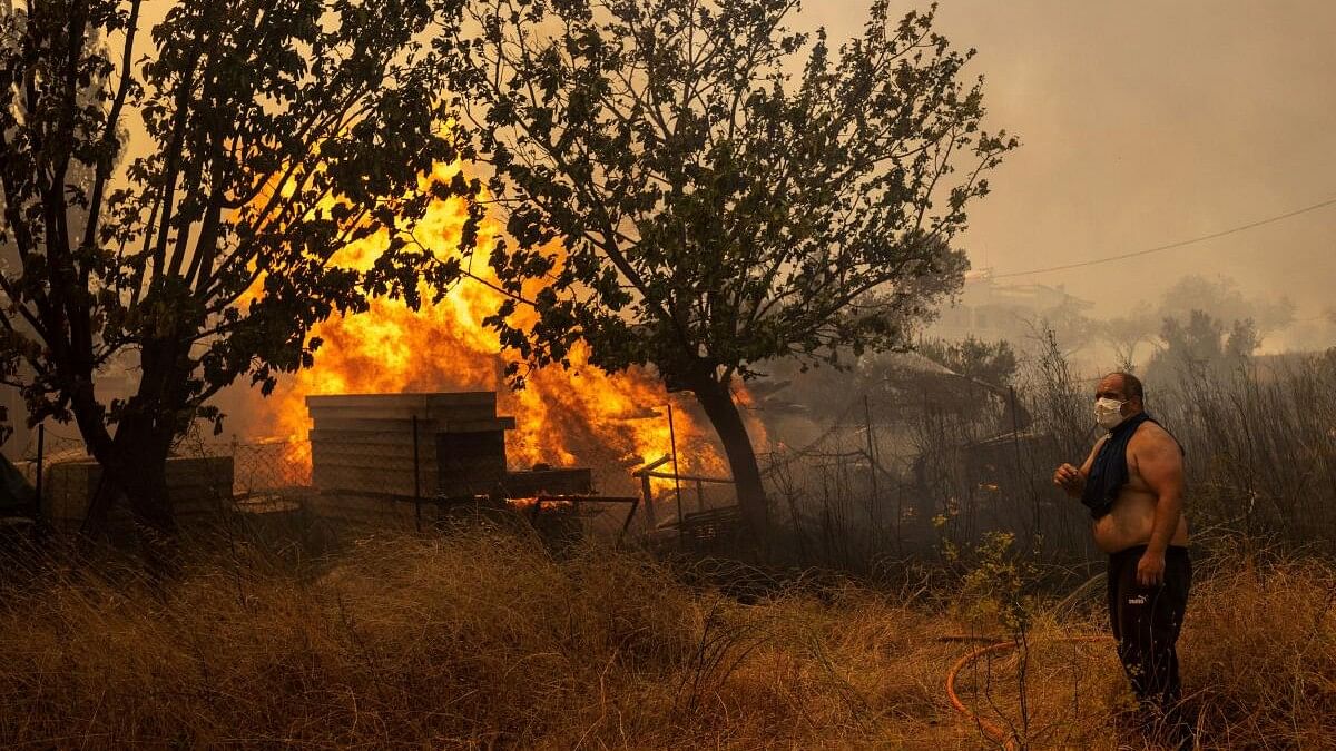 <div class="paragraphs"><p>A volunteer stands next to rising flames as a wildfire burns in Hasia village, near Athens, Greece, August 22, 2023.</p></div>