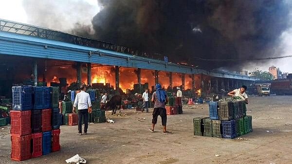 <div class="paragraphs"><p>People stand near a fire breaking out at the Azadpur Mandi, in New Delhi.</p></div>