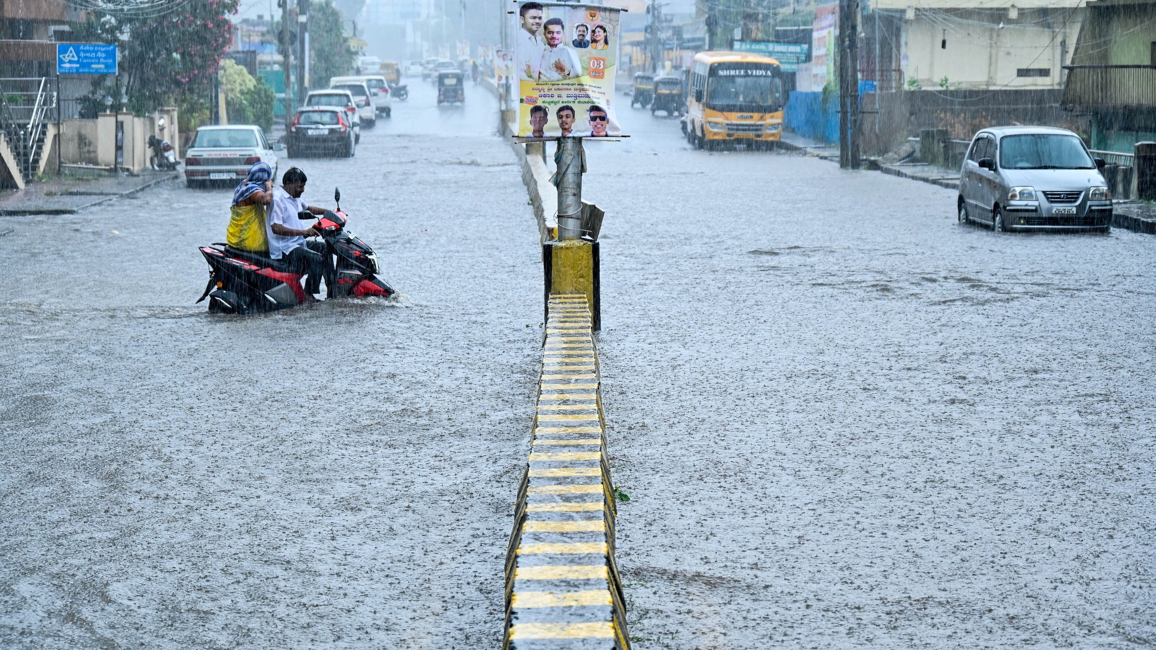 <div class="paragraphs"><p>A motorist struggles to negotiate the flooded Sharanabasaveshwara Temple road near court in Kalaburagi on Sunday. The city and several parts of the district are experiencing heavy showers since Saturday night. </p></div>