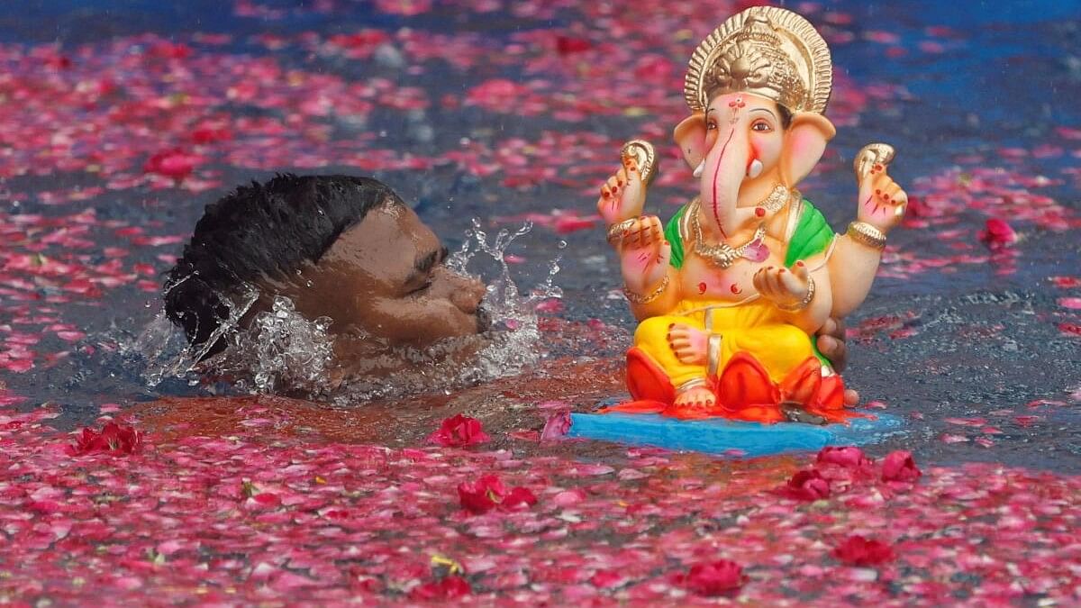 <div class="paragraphs"><p>A man immerses an idol of Ganesh in an artificial pond during the ten-day-long Ganesh Chaturthi festival in Mumbai.</p></div>