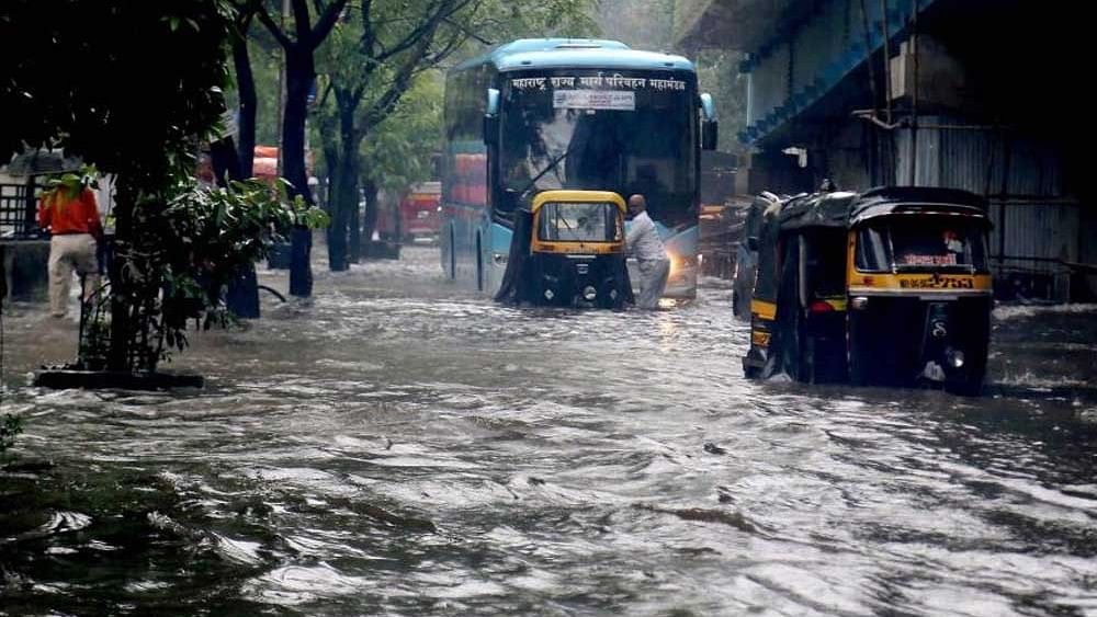 <div class="paragraphs"><p>Vehicles wade through a flooded road after heavy rains in Thane district.</p></div>