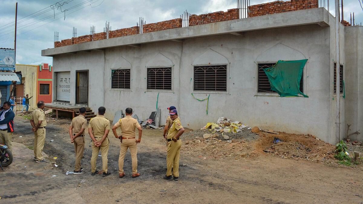 <div class="paragraphs"><p>Police personnel stand guard after a clash between two groups over a controversial post on social media, at Pusesavali in Satara district.</p></div>
