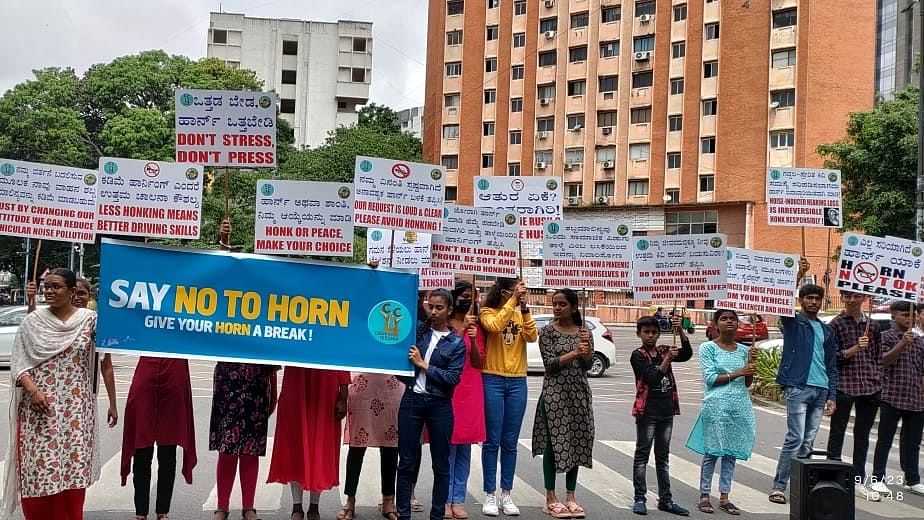 <div class="paragraphs"><p>Students of RC College in the city display placards to raise awareness about the ill effects of honking at Basaveshwara Circle on Wednesday. </p></div>