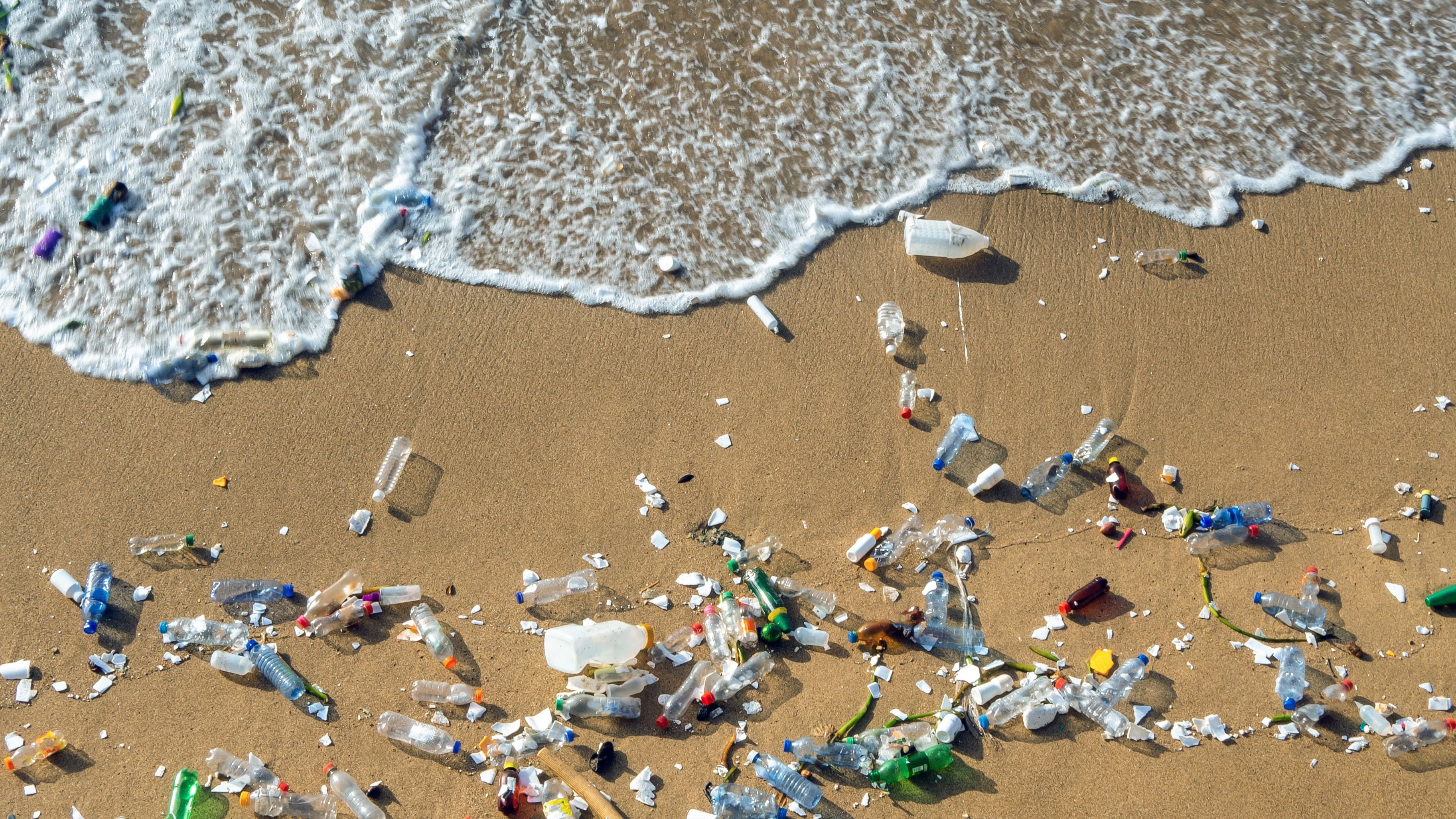 Plastic waste polluting the beach, mostly bottles that are pushed and attracted to the waves.