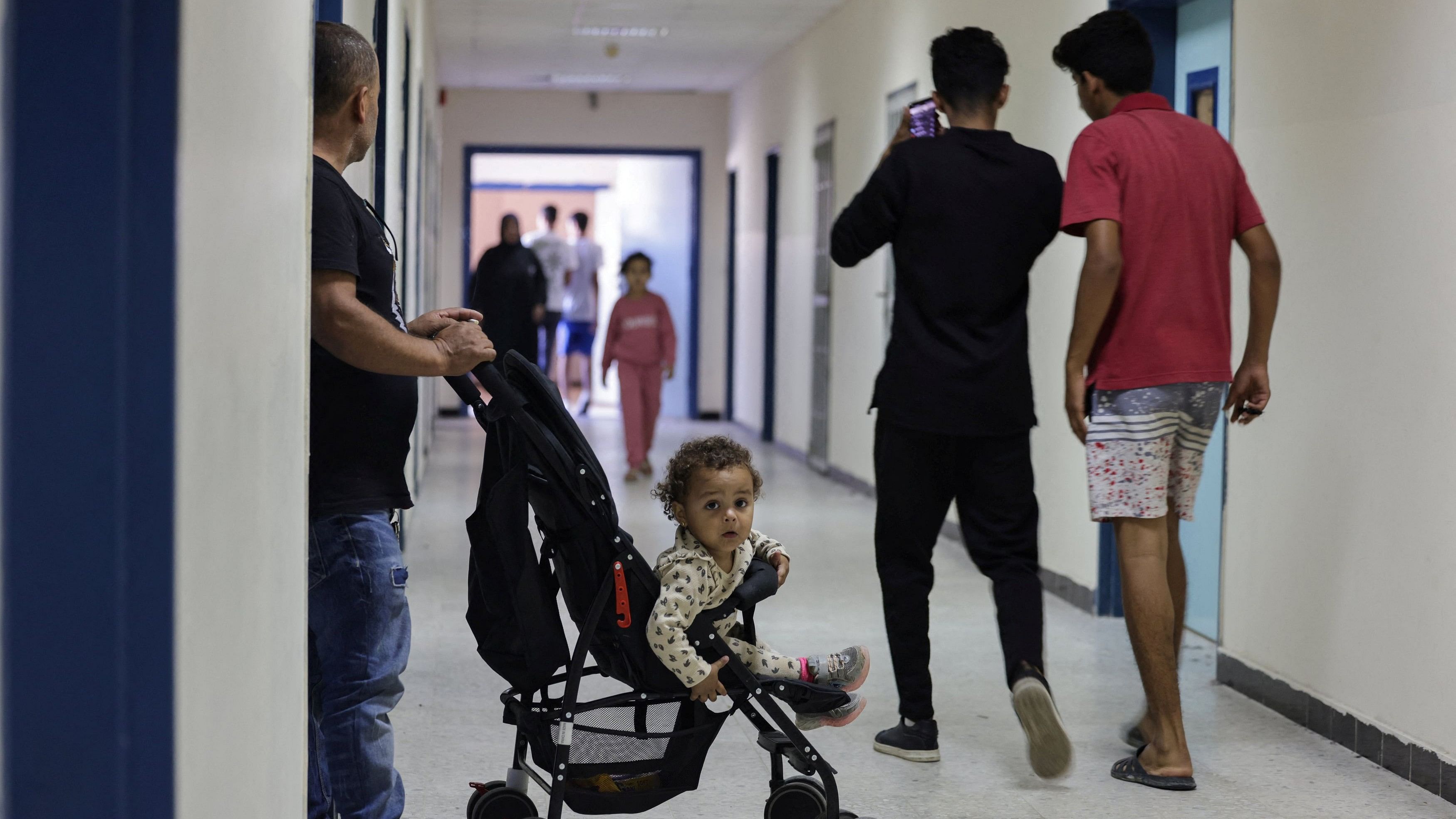 <div class="paragraphs"><p>A man who said he escaped from the south Lebanese village of Aitaroun, near the Israeli border, holds a stroller with his daughter at a school where they take refuge in Tyre, October 21, 2023.</p></div>