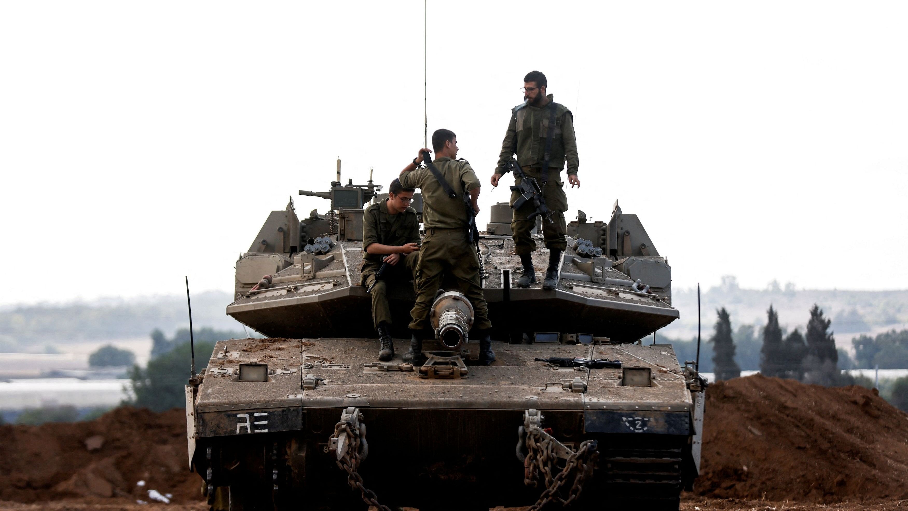 <div class="paragraphs"><p>Israeli soldiers chat while on top of an Israeli tank near Israel's border with the Gaza Strip, in southern Israel.</p></div>