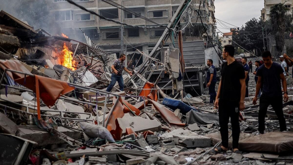 <div class="paragraphs"><p>Palestinians watch a fire burn among the rubble of a damaged residential building, in the aftermath of Israeli strikes, in Gaza City.</p></div>