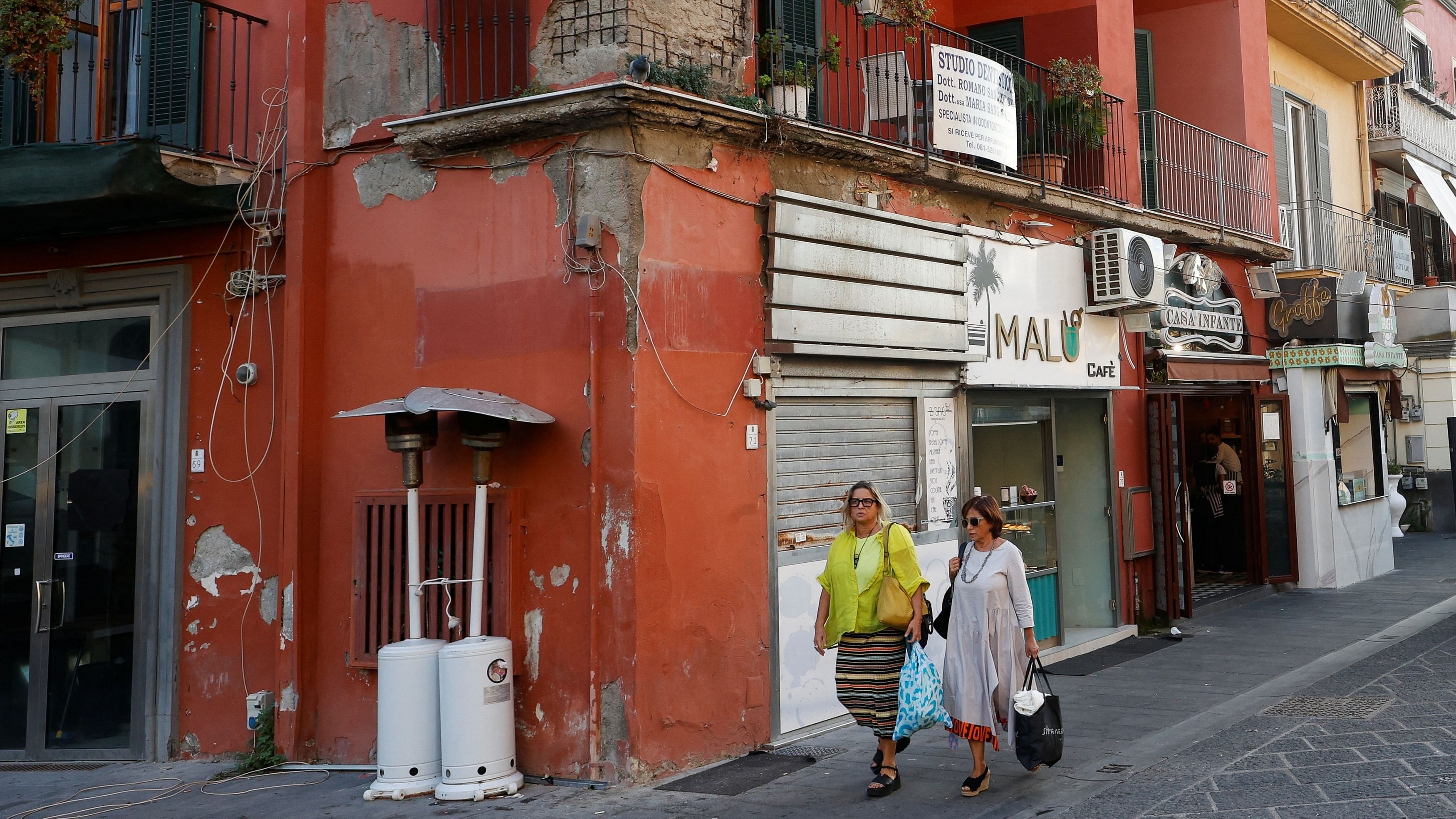 <div class="paragraphs"><p>Women walk past damaged building on a street, amidst the Italian government's plan for a possible mass evacuation of people who live around the supervolcano near Naples.</p></div>