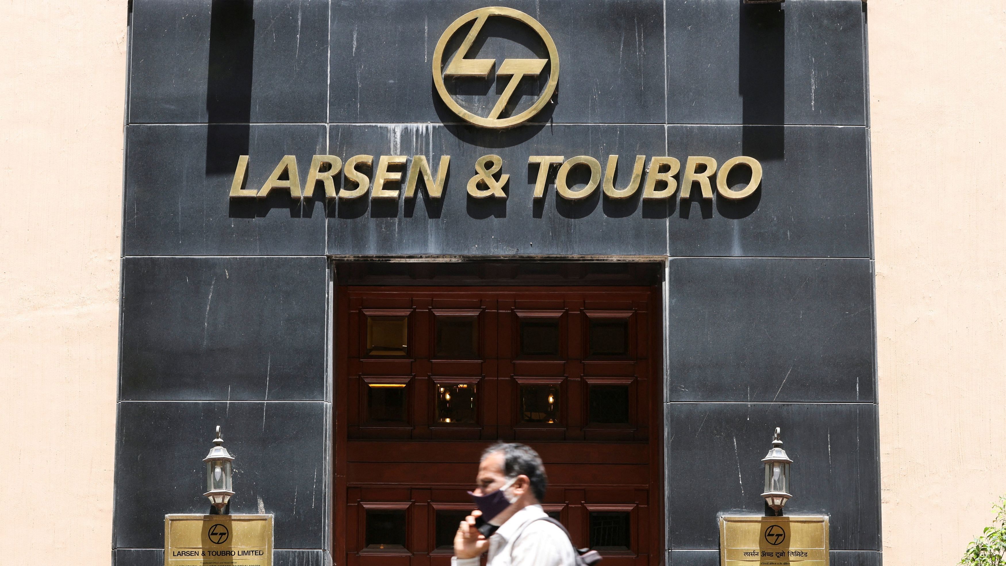 <div class="paragraphs"><p>A man walks past the Larsen &amp; Toubro logo.</p></div>