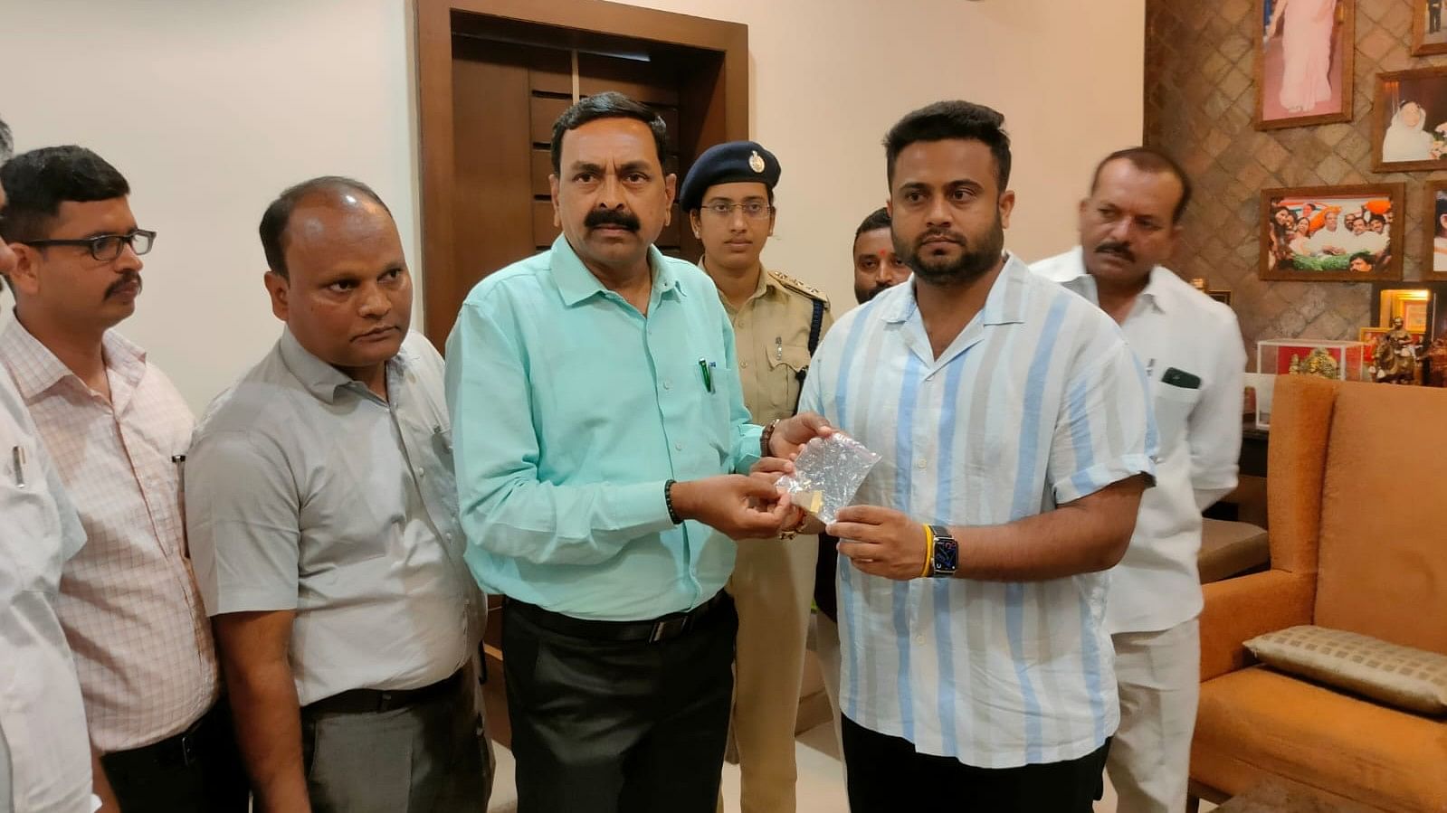 <div class="paragraphs"><p>Woman and Child Welfare Minister Laxmi Hebbalkar's son Mrinal handing over tiger claw-like pendant to Forest Department officials during search at the minister's residence in Belagavi on Friday.  </p></div>