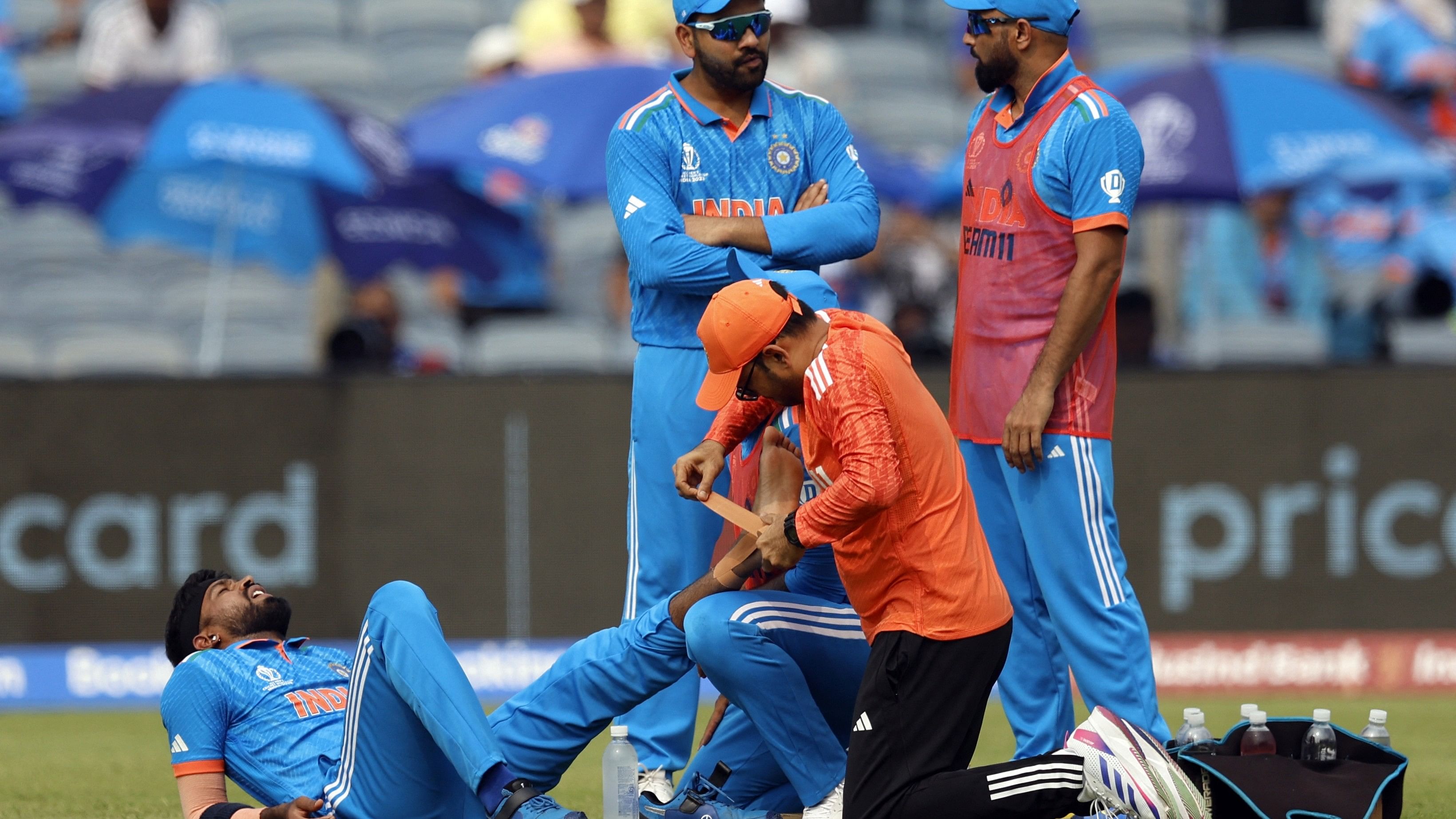 <div class="paragraphs"><p>Hardik Pandya (left) receives medical attention after sustaining an injury&nbsp;when he attempted to stop a straight drive in his bowling over as Rohit Sharma and Mohammed Shami look on.</p></div>