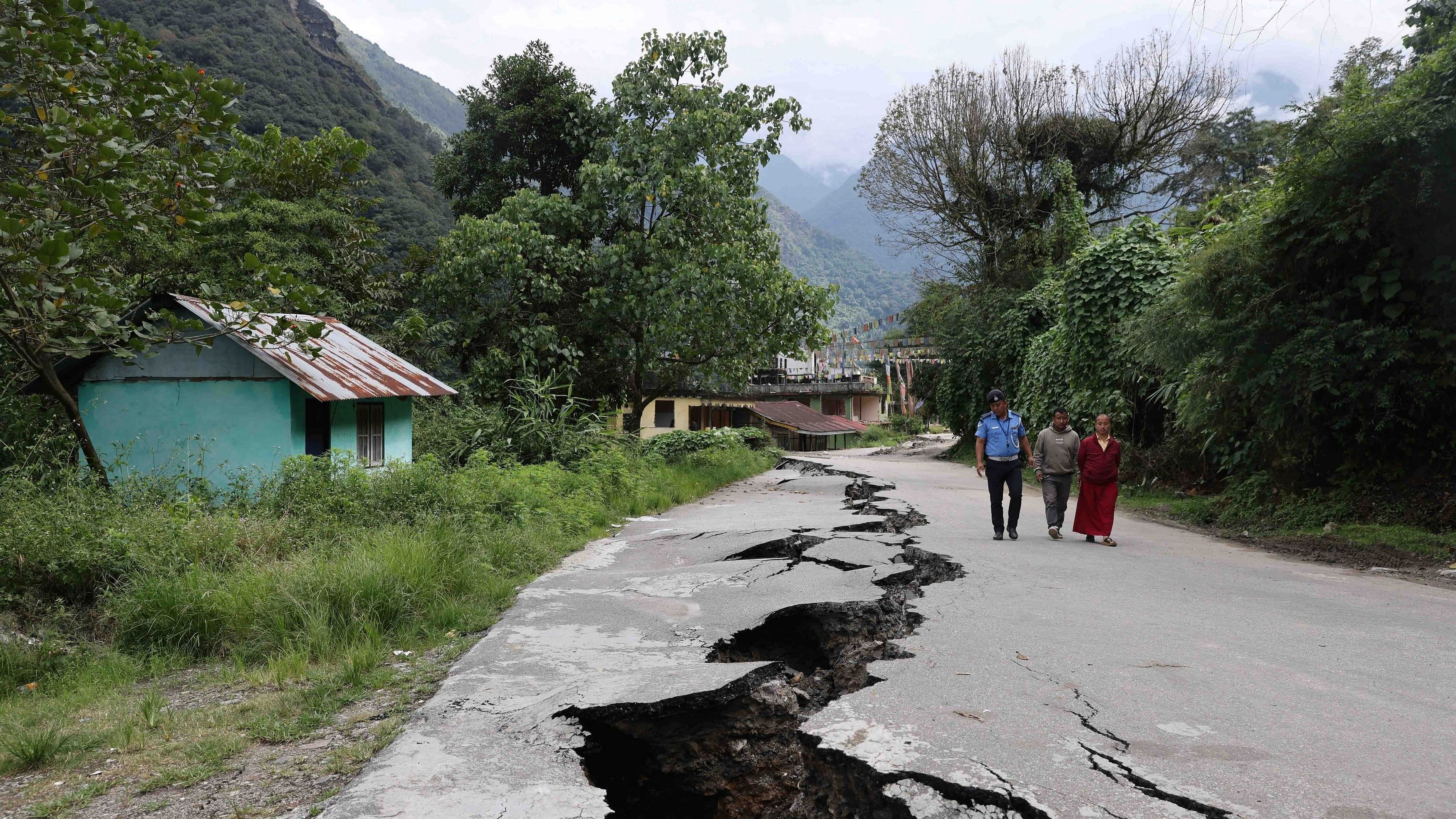 <div class="paragraphs"><p>People walk along a road with cracks caused by flash floods in Naga-Namgor village, Sikkim, India.</p></div>