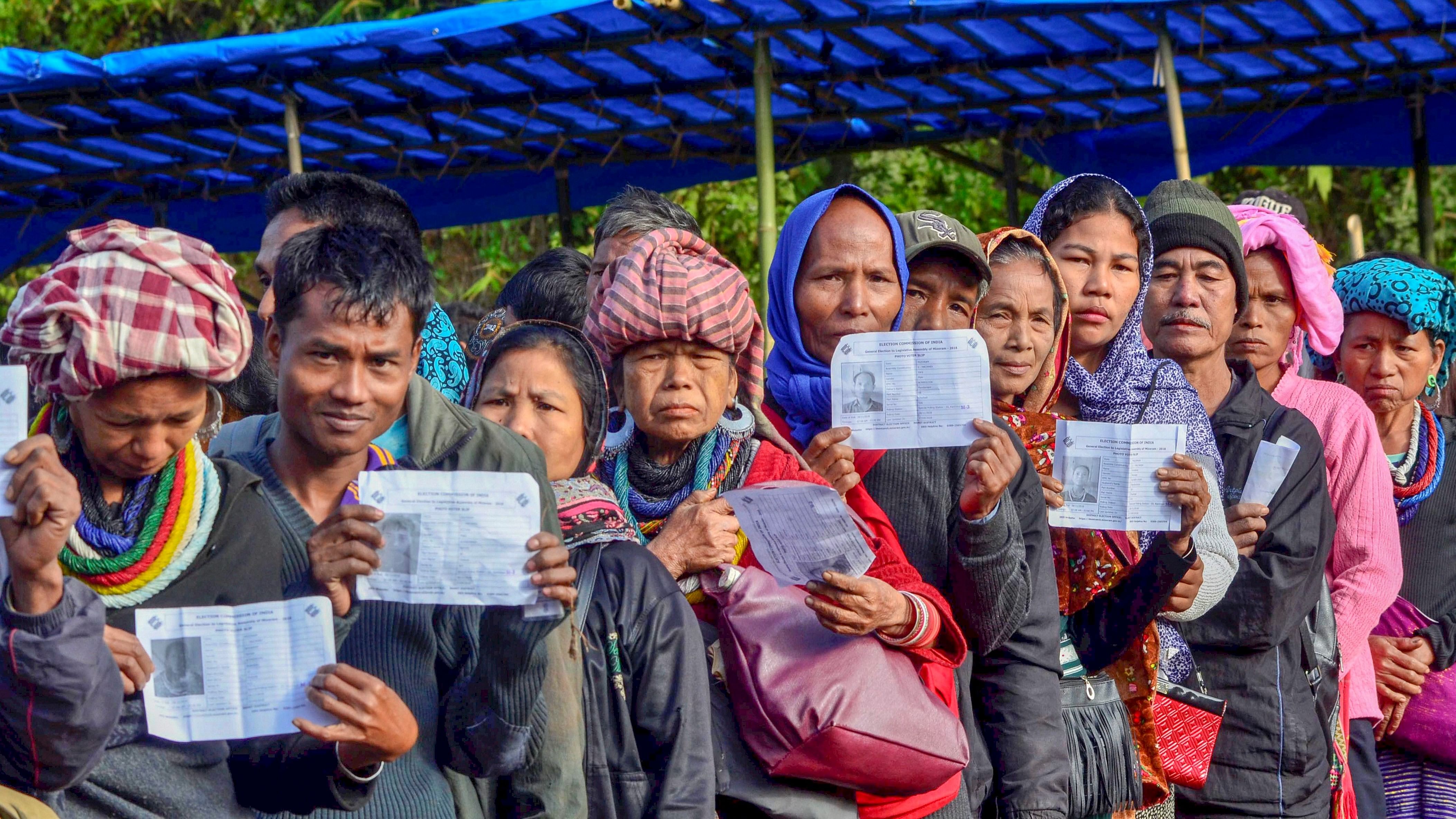 <div class="paragraphs"><p>Voters show their identity card as they stand in a queue at a polling station during the state Assembly elections, at Kanhmun, Mizoram.&nbsp;</p></div>