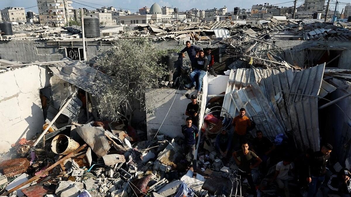 <div class="paragraphs"><p>Palestinians stand among debris as they search for bodies at the site of an Israeli strike, amid the ongoing conflict between Israel and Palestinian Islamist group Hamas.</p></div>