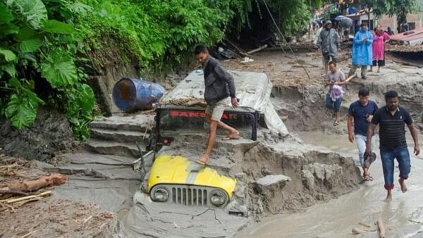 <div class="paragraphs"><p>People walk along a street as a jeep is buried in the mud due to the flood at Teesta Bazaar in Kalimpong District, West Bengal.</p></div>