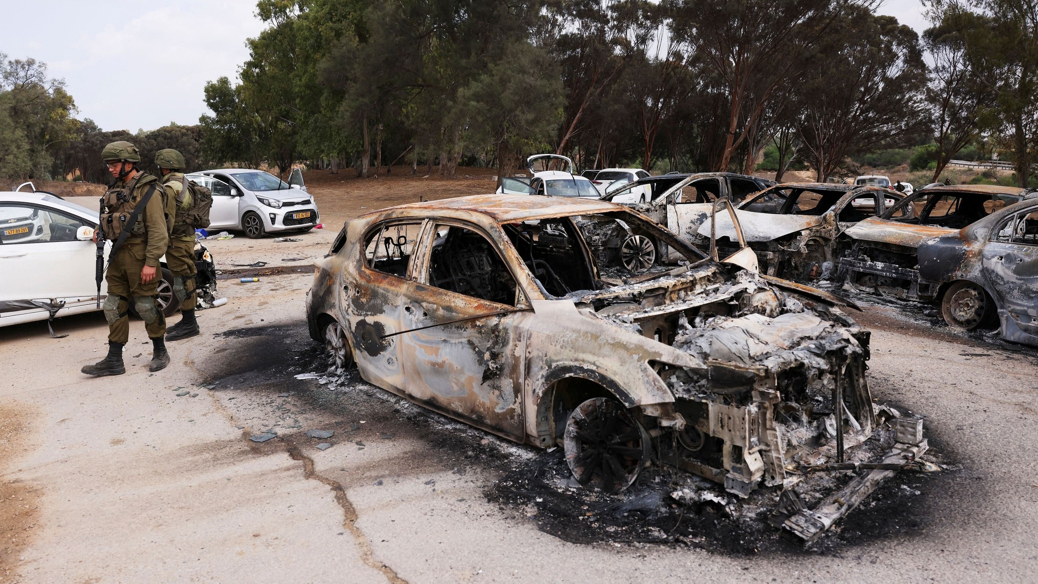 <div class="paragraphs"><p>Israeli soldiers inspect burnt cars that were abandoned in a carpark near where a festival was held before an attack by Hamas gunmen from Gaza, by Israel's border with Gaza in southern Israel, October 10, 2023. </p></div>