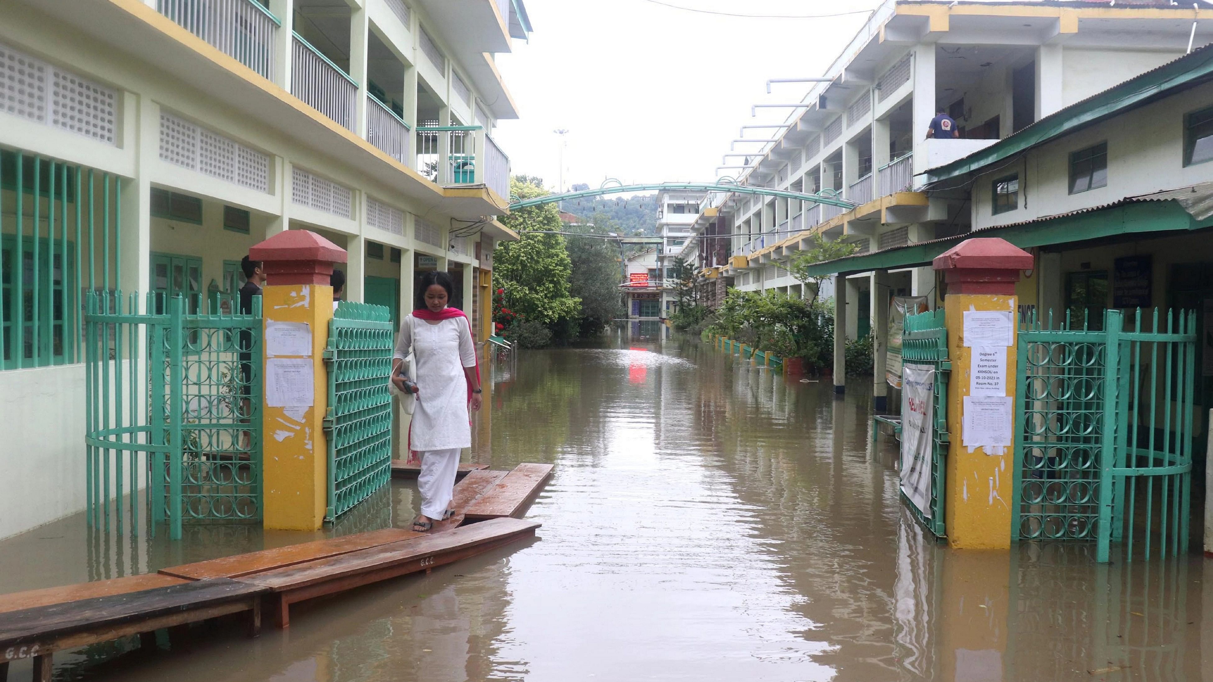 <div class="paragraphs"><p>Guwahati: A student walks on a temporary bridge at the waterlogged campus of a college after heavy rains, in Guwahati.</p></div>