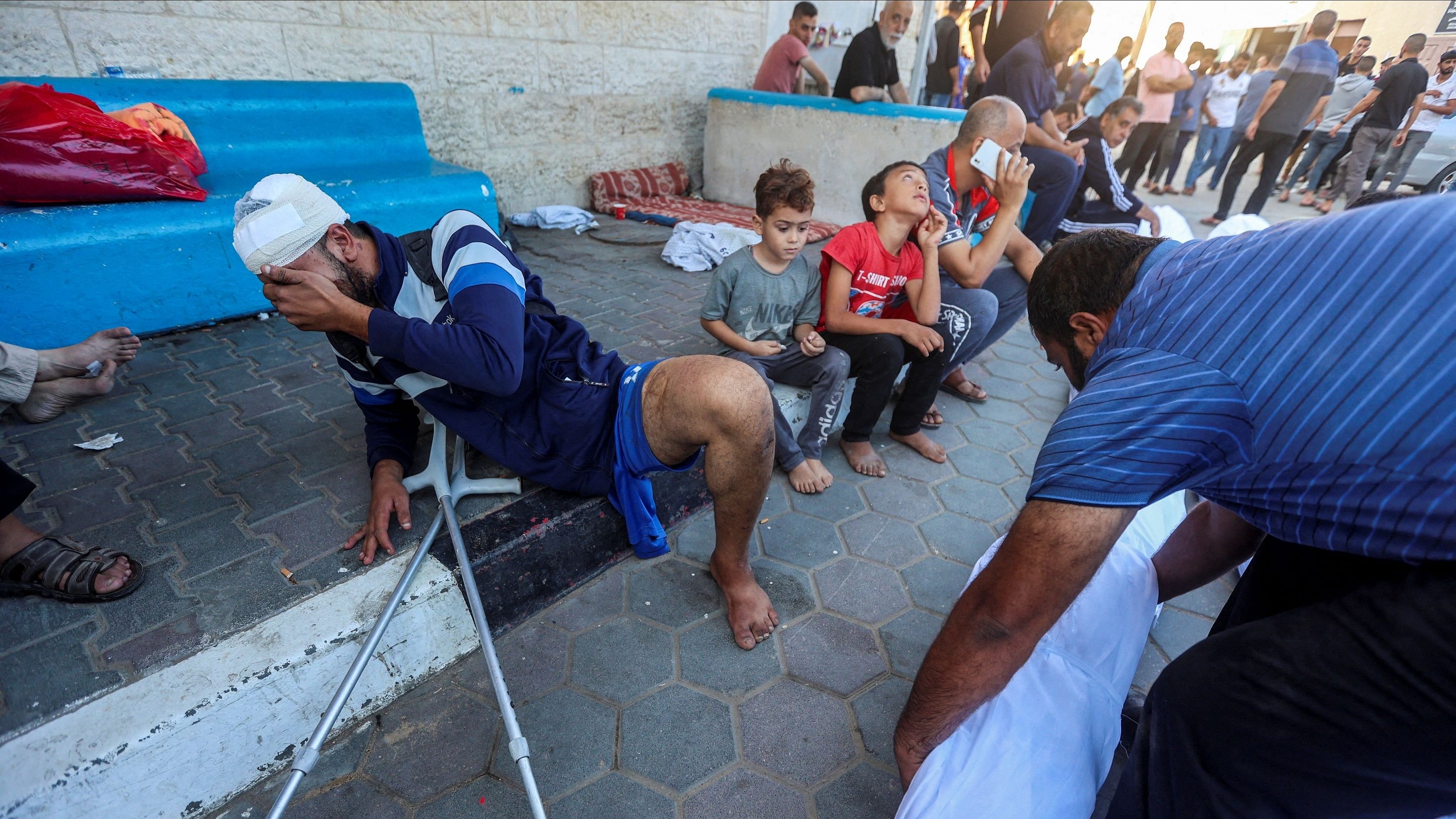 <div class="paragraphs"><p>A Palestinian man wounded in Israeli strikes reacts next to the bodies of his relatives who were killed in the strikes, at Shuhada Al-Aqsa hospital in the central Gaza Strip.</p></div>