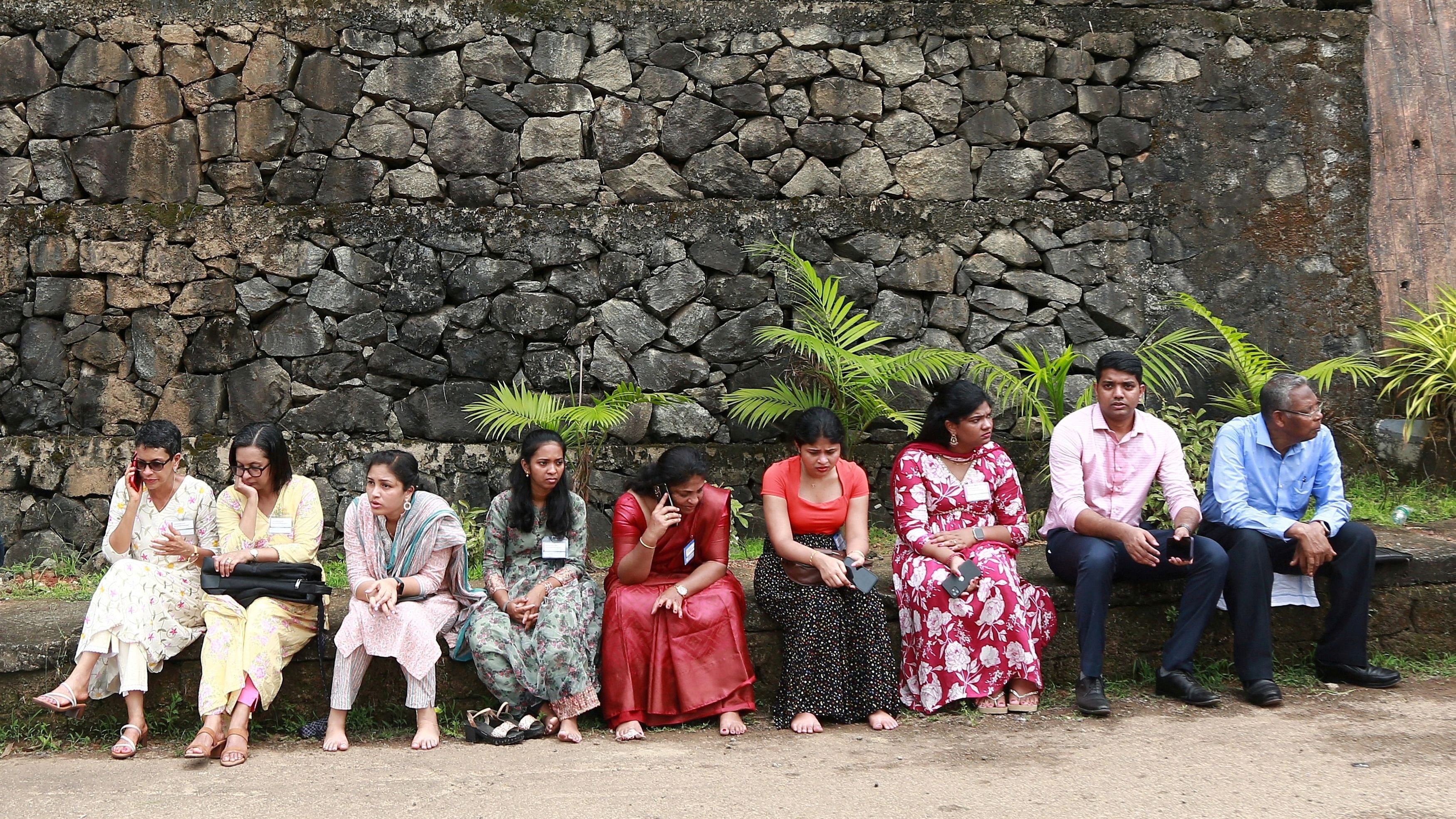 <div class="paragraphs"><p>People sit outside the Zamra International Convention and Exhibition Centre after being evacuated from the centre following multiple blasts during a religious gathering of Jehovah's Witnesses, a Christian group, in Kochi</p></div>