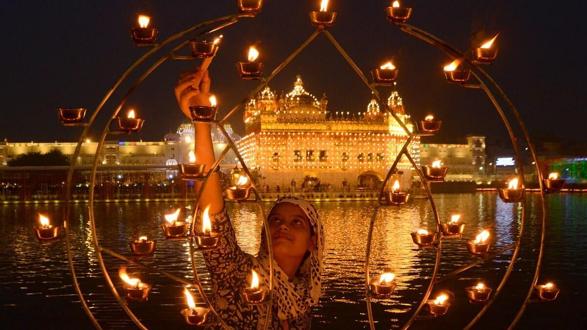 <div class="paragraphs"><p>A devotee lights 'diyas' at Golden Temple on the birth anniversary of the Sikh Guru Ram Das, in Amritsar. </p></div>