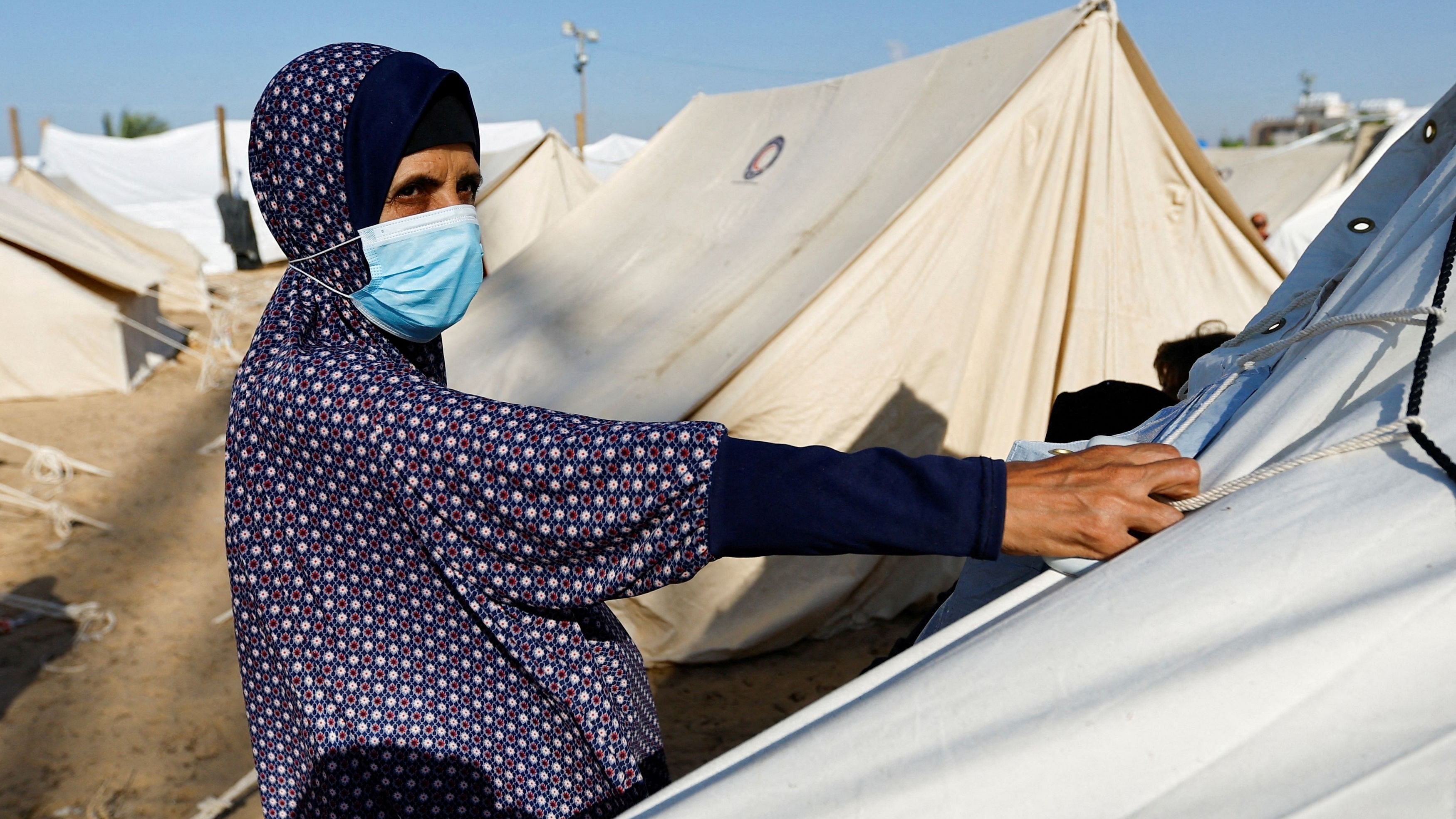 <div class="paragraphs"><p>A woman wearing a face mask looks on as Palestinians, who fled their houses amid Israeli strikes, take shelter in a tent camp at a United Nations-run centre, after Israel's call for more than 1 million civilians in northern Gaza to move south, in Khan Younis in the southern Gaza Strip, October 19, 2023. </p></div>