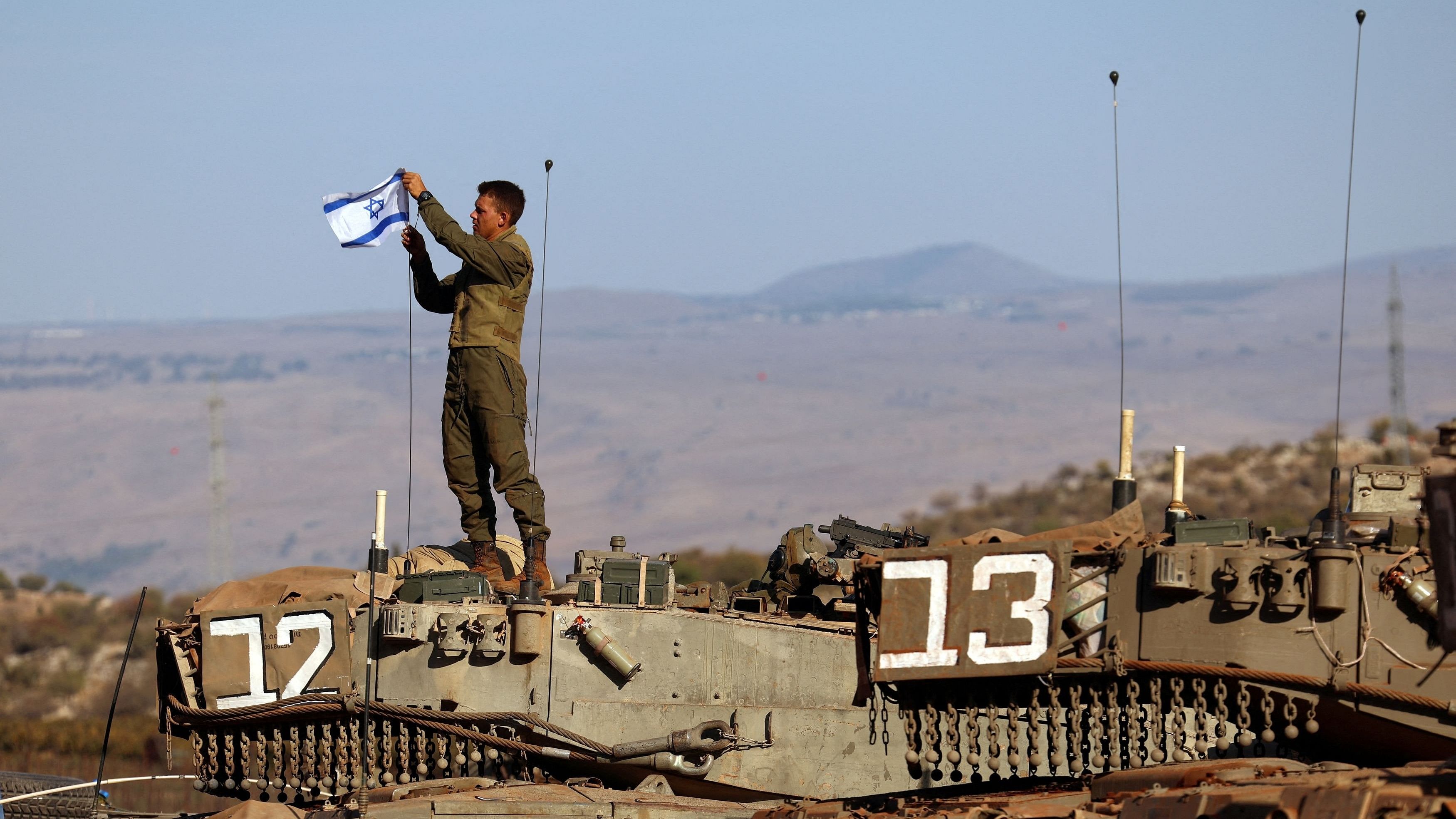 <div class="paragraphs"><p>A soldier installs an Israeli flag on a tank during a military drill.</p></div>