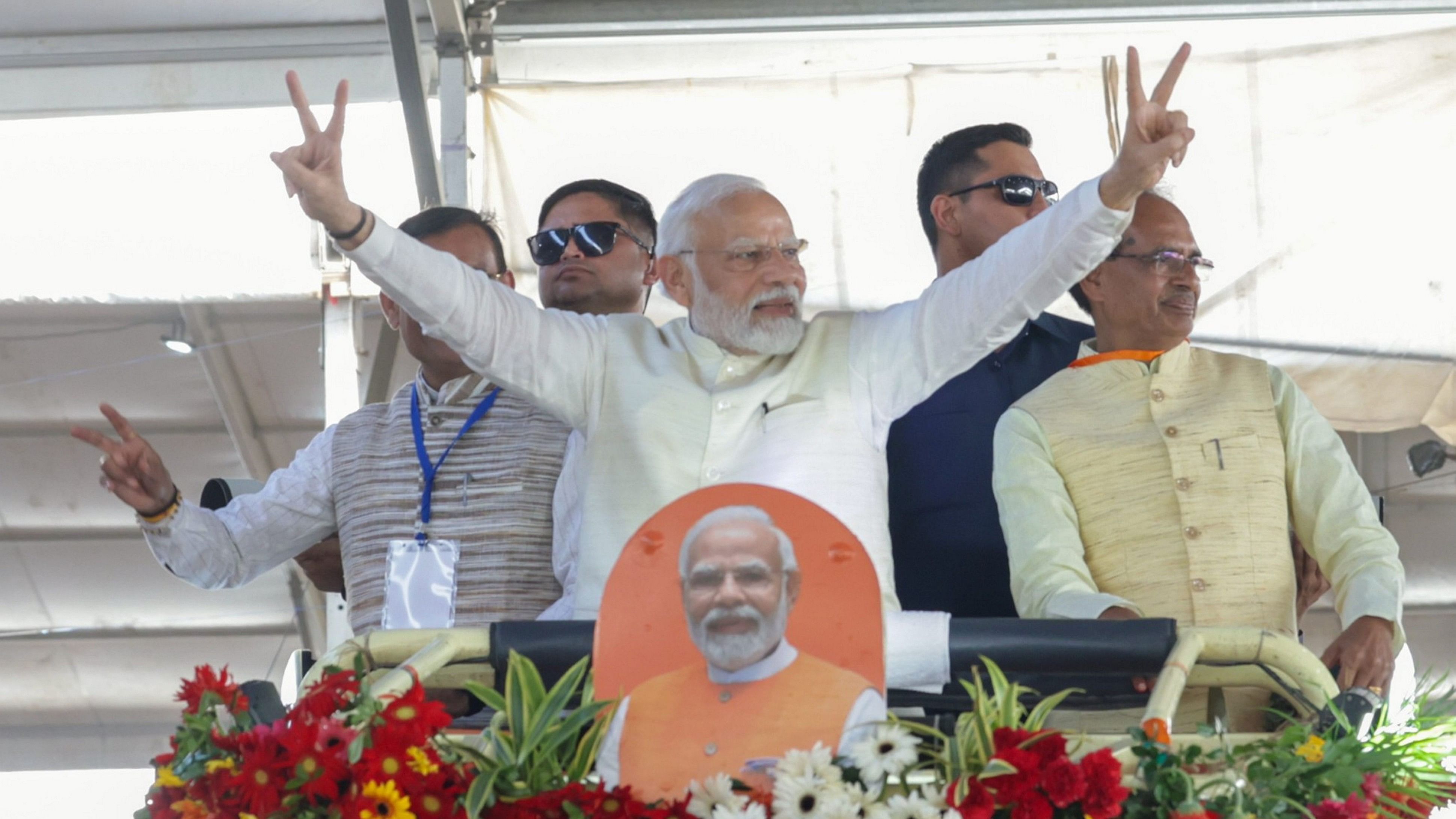 <div class="paragraphs"><p>PM Narendra Modi flashes the victory sign as he arrives for an event in Gwalior on October 2. Madhya Pradesh Chief Minister Shivraj Singh Chouhan and MP BJP president VD Sharma are also seen. </p></div>