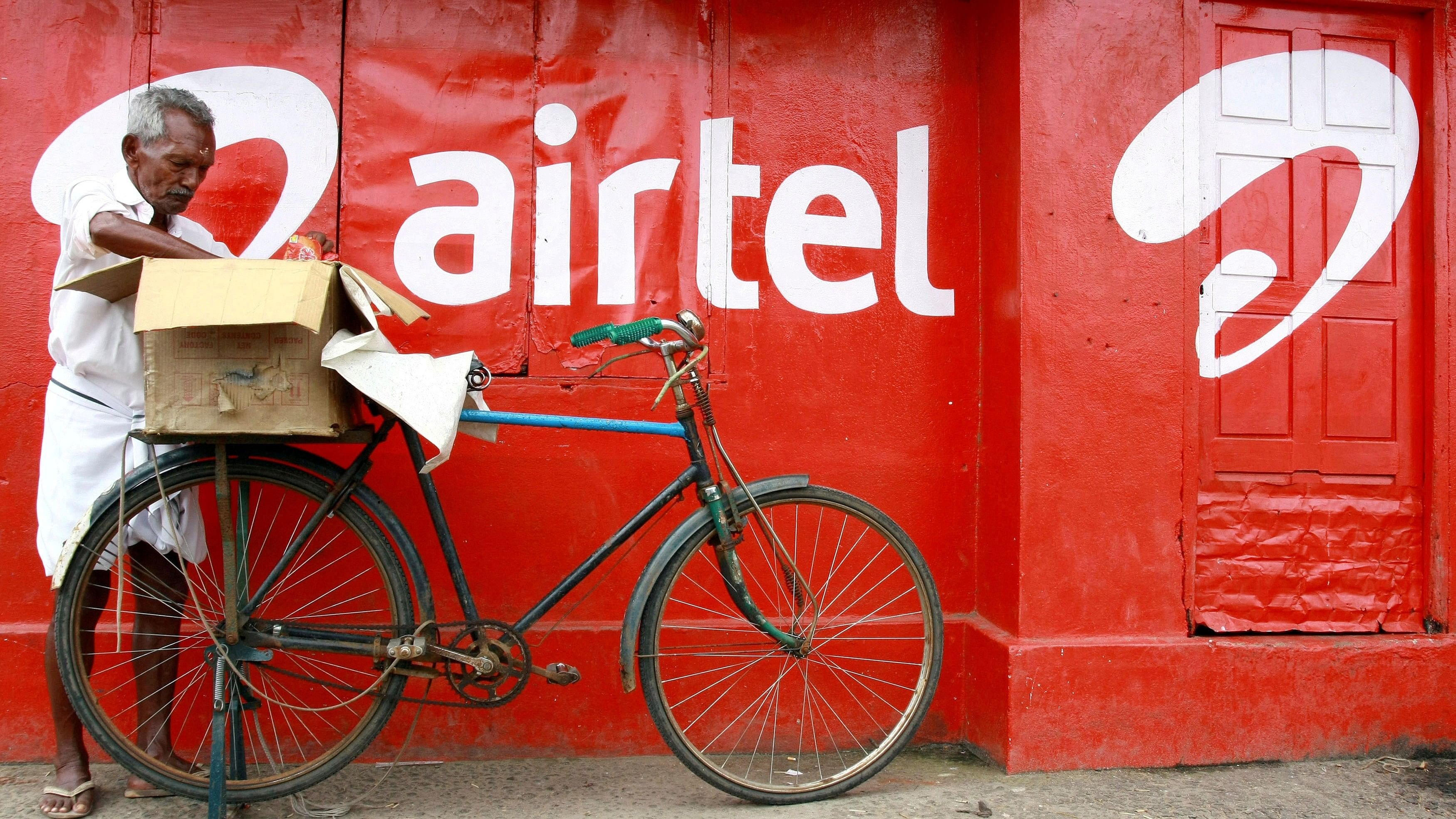 <div class="paragraphs"><p>A man packs goods on the back of his bicycle as he stands next to the wall of a grocery shop painted with an advertisement for Bharti Airtel in the southern Indian city of Kochi</p></div>