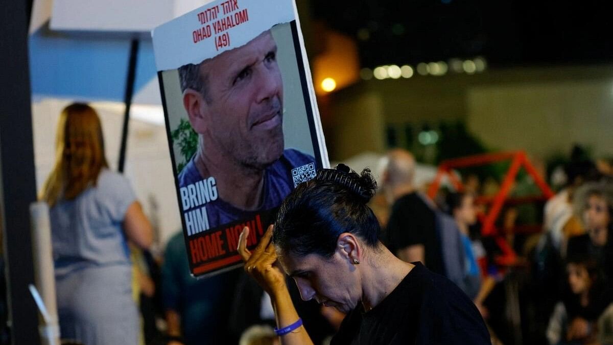 <div class="paragraphs"><p>A woman holds a placard as people await news of hostages expected to be released by Hamas, amid a hostages-prisoners swap deal between Hamas and Israel, in Tel Aviv, Israel.&nbsp;</p></div>