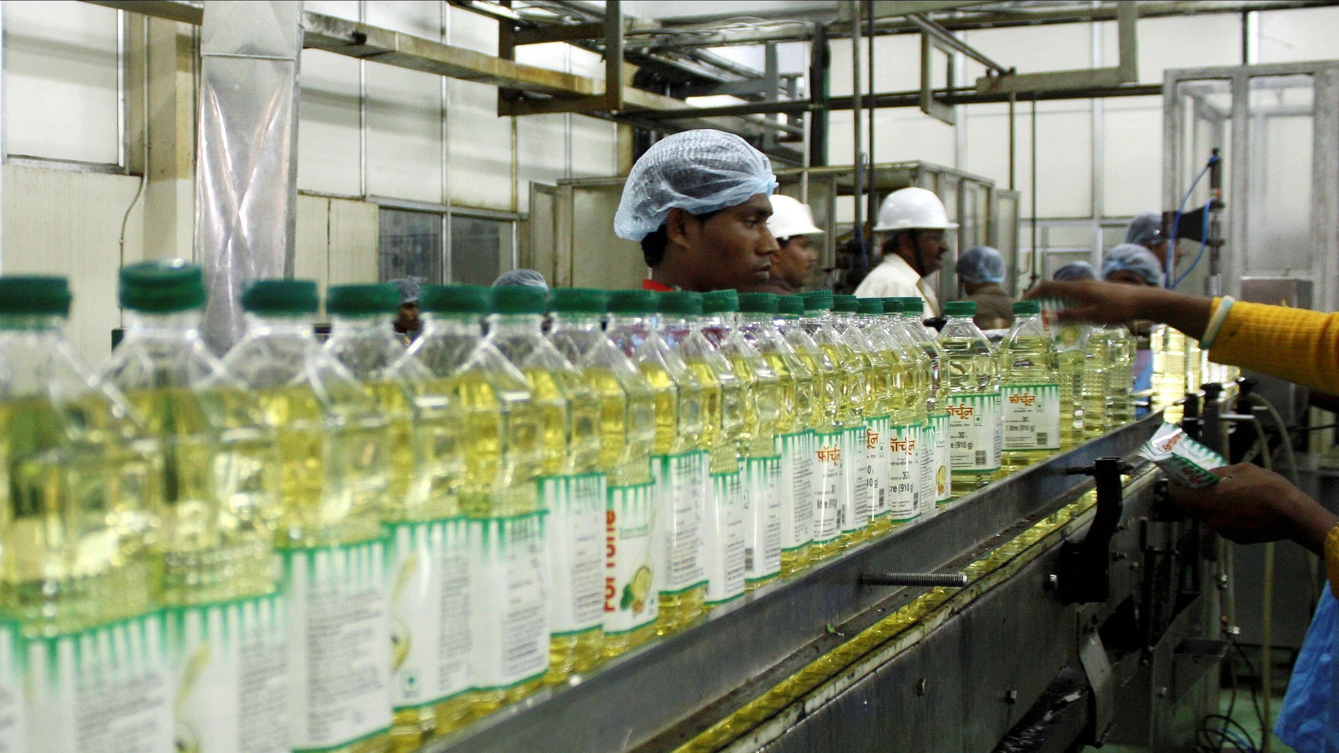 <div class="paragraphs"><p>Employees fill plastic bottles with edible oil at an oil refinery plant of Adani Wilmar Ltd.</p></div>