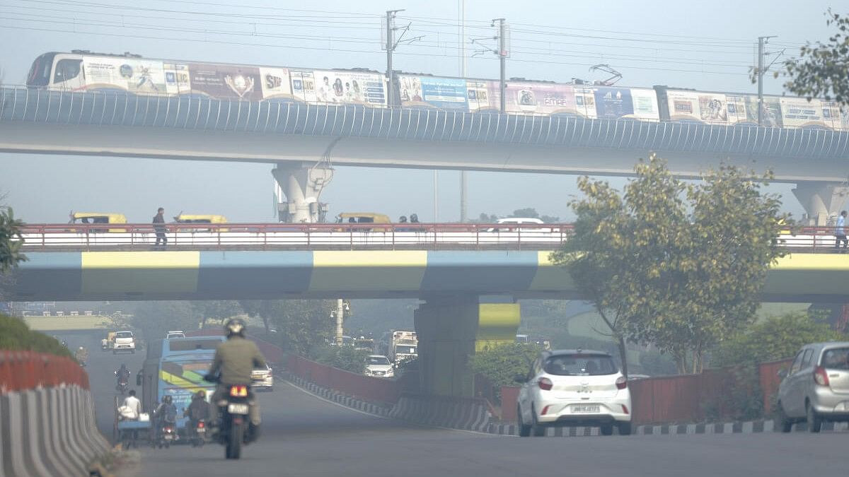 <div class="paragraphs"><p>A metro train runs on its track as vehicles ply on a road amid smog, at Dhaula Kuan in New Delhi.</p></div>
