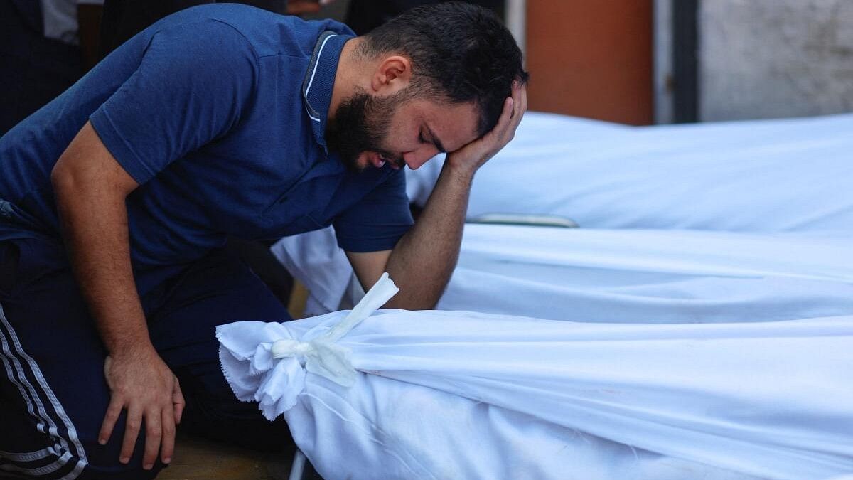 <div class="paragraphs"><p>A man next to the bodies of Palestinians killed in Israeli strikes at a hospital, in the Gaza Strip,</p></div>