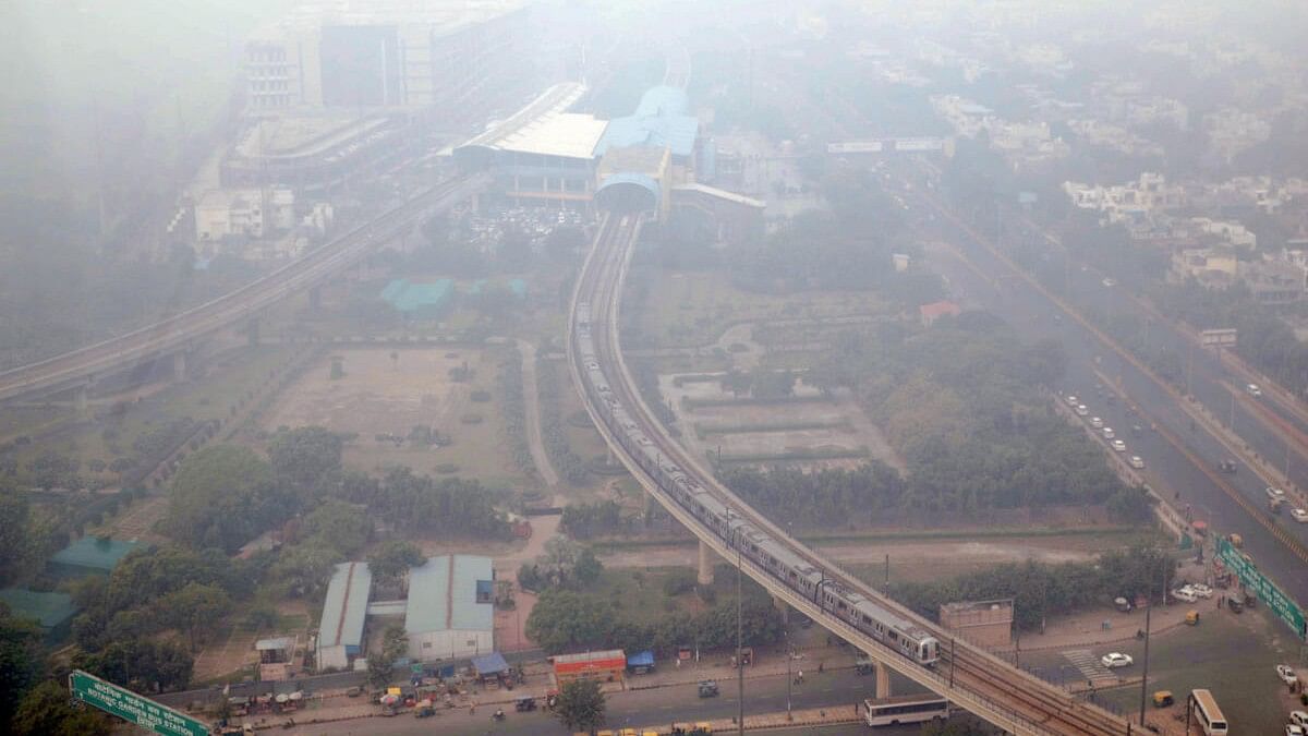 <div class="paragraphs"><p>A metro train runs on its track amid smog, in Noida.</p></div>