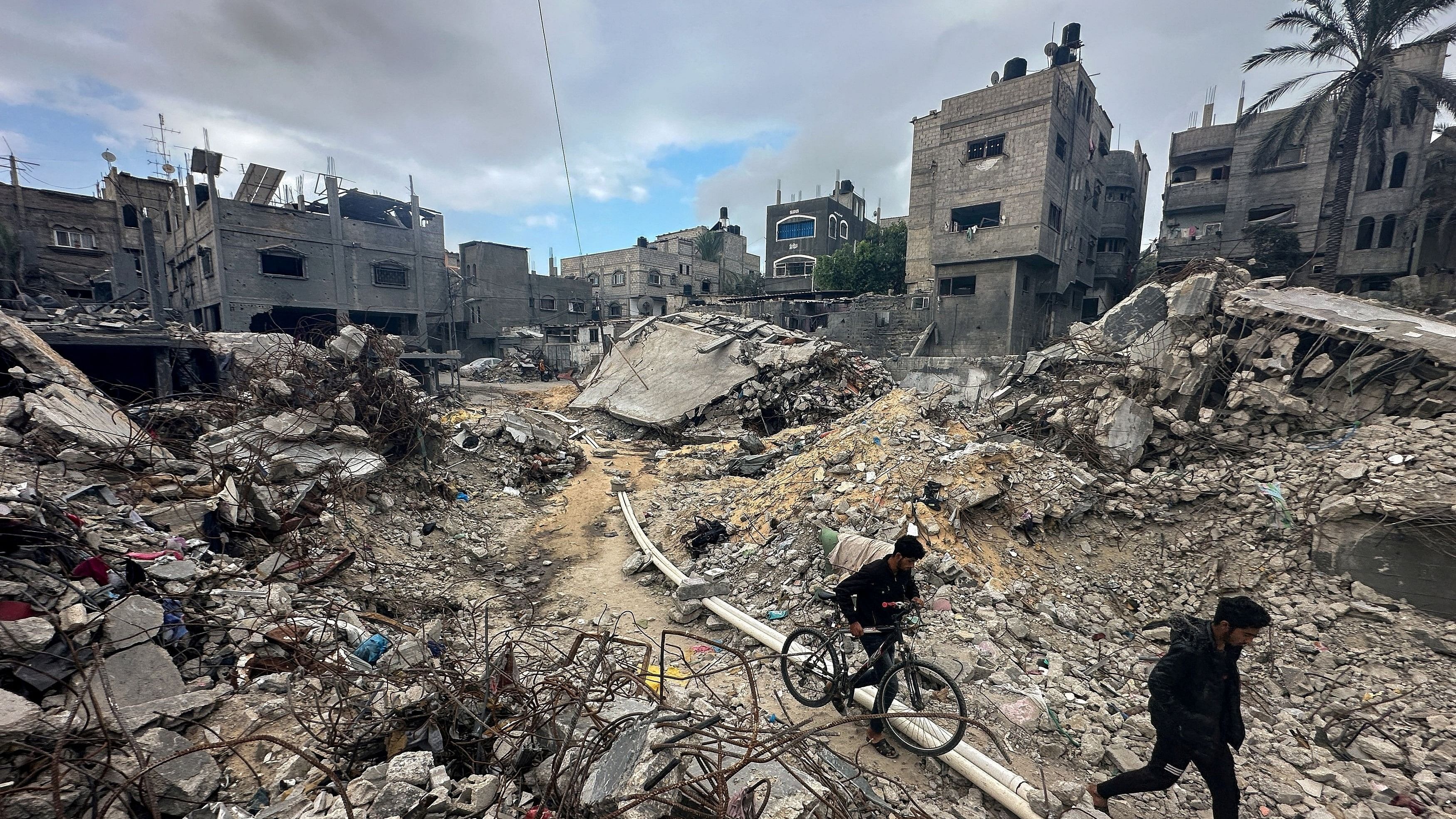 <div class="paragraphs"><p>Palestinians walk among the rubble, as they inspect houses destroyed in Israeli strikes during the conflict, amid the temporary truce between Hamas and Israel, at Khan Younis refugee camp in the southern Gaza Strip November 27, 2023. </p></div>