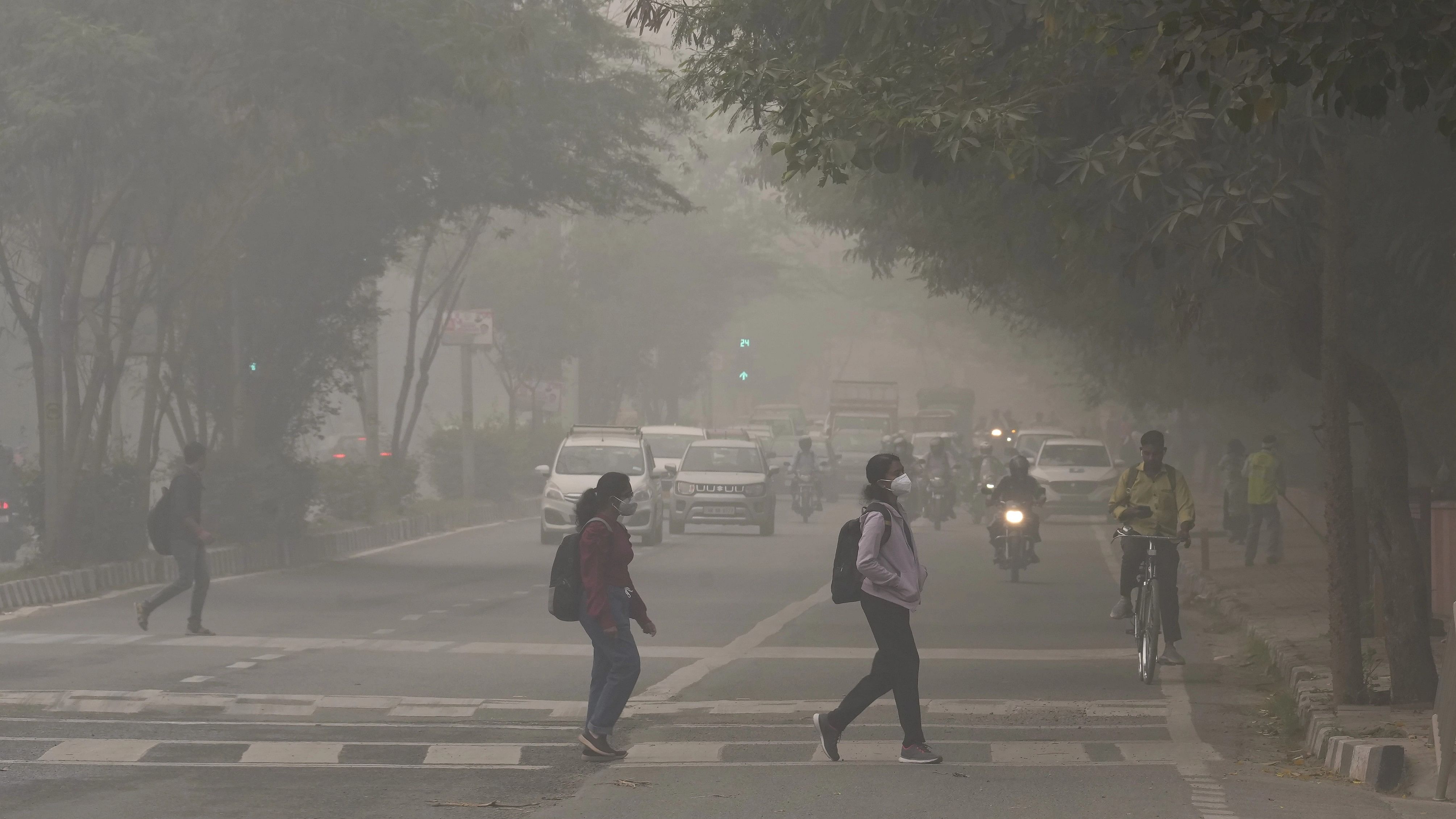 <div class="paragraphs"><p>New Delhi: Students wearing anti-pollution masks cross a road amid hazy weather conditions, in New Delhi. Delhi-NCR's air quality neared the emergency threshold on Thursday, prompting an immediate ban on non-essential construction work and the closure of primary schools in the capital. </p></div>