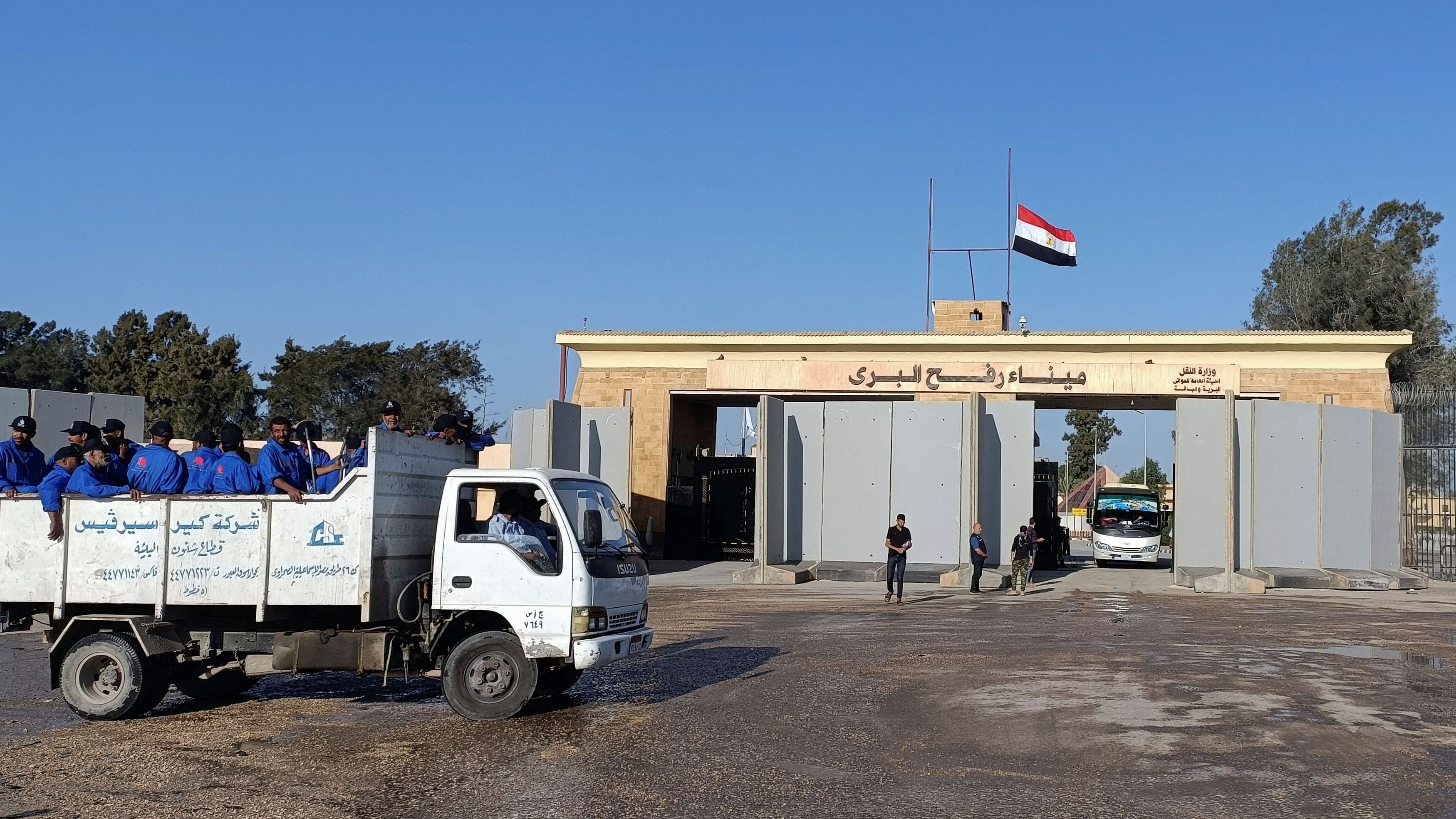 <div class="paragraphs"><p>Egyptian cleaning workers are seen in front of the Rafah crossing from the Egyptian side, while trucks carrying humanitarian aid for Palestinians await for it to open to enter Gaza.</p></div>