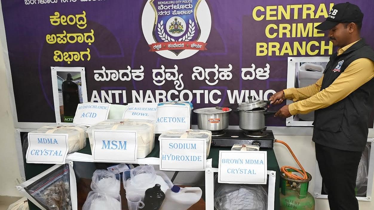 <div class="paragraphs"><p>A CCB sleuth inspects the items seized from (inset) Benjamin Chidubem’s studio apartment in Bengaluru on Friday.</p></div>