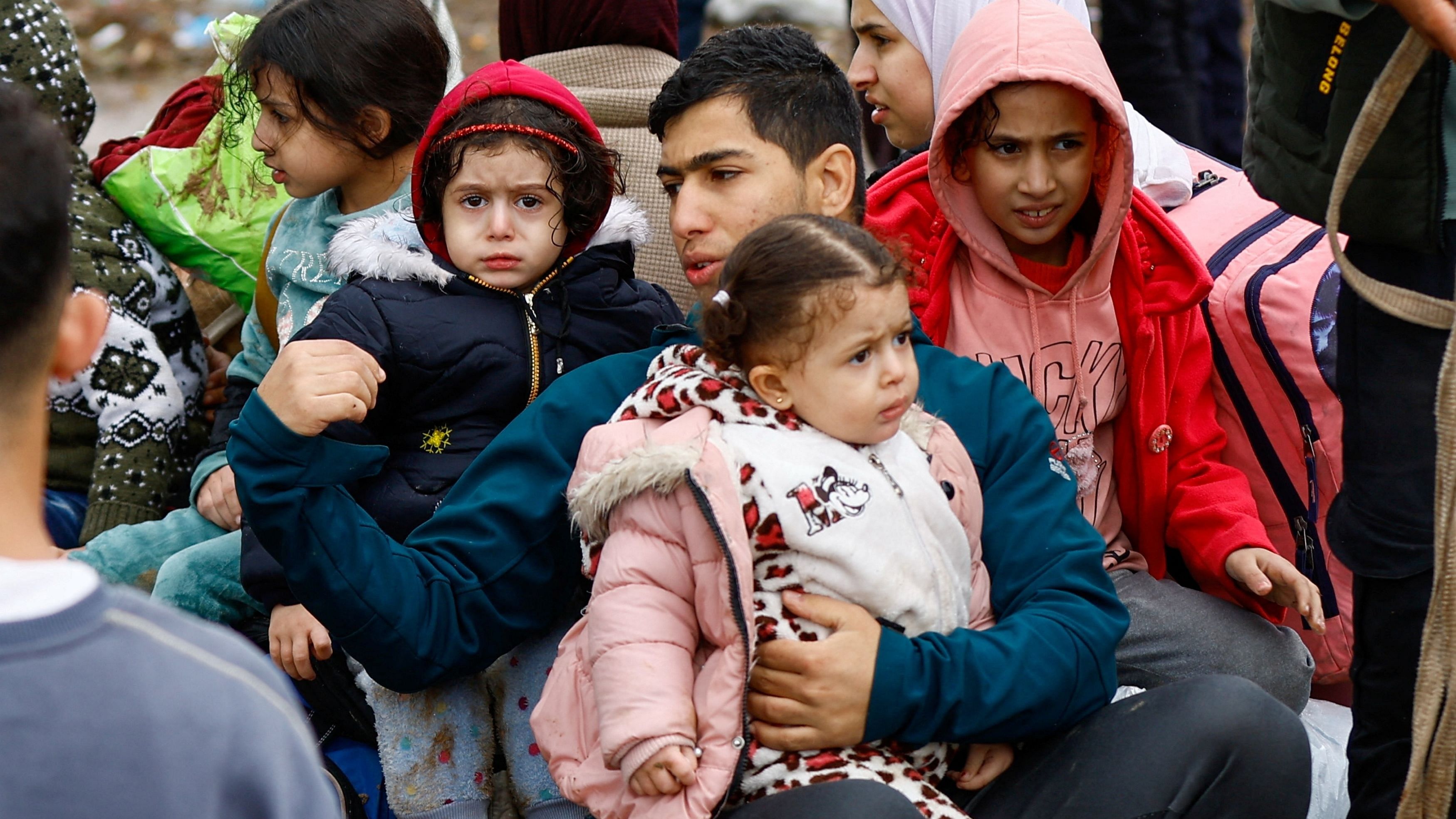 <div class="paragraphs"><p>A man sits with children, as Palestinians fleeing north Gaza move southward during a temporary truce between Israel and Hamas, near Gaza City, November 27, 2023. </p></div>