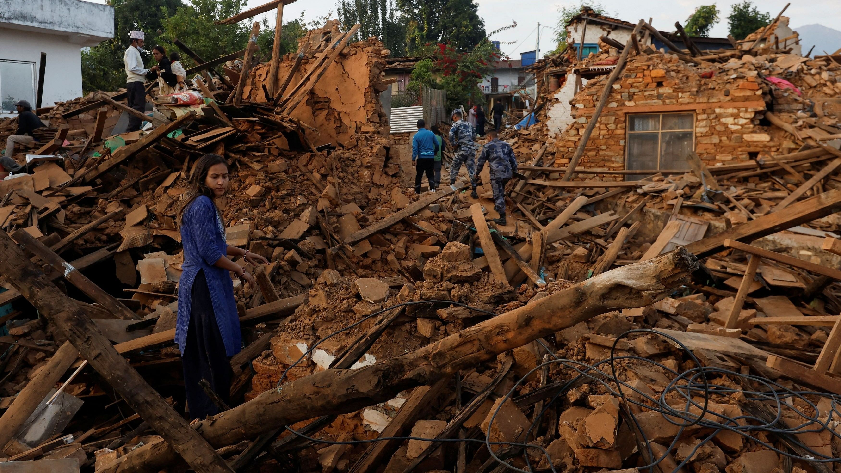 <div class="paragraphs"><p>A woman stands on top of the debris of her house that collapsed during an earthquake in Jajarkot, Nepal.</p></div>