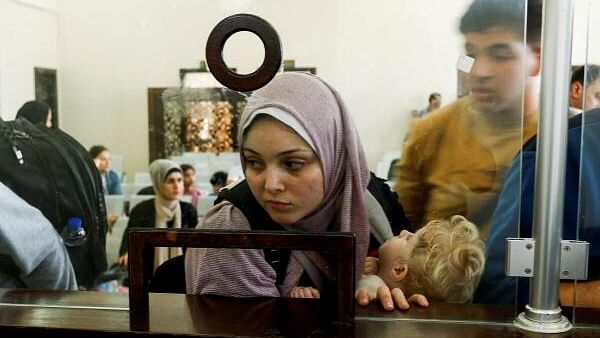 <div class="paragraphs"><p>A Palestinian holding a foreign passport looks through a counter as she waits for permission to leave Gaza.</p></div>