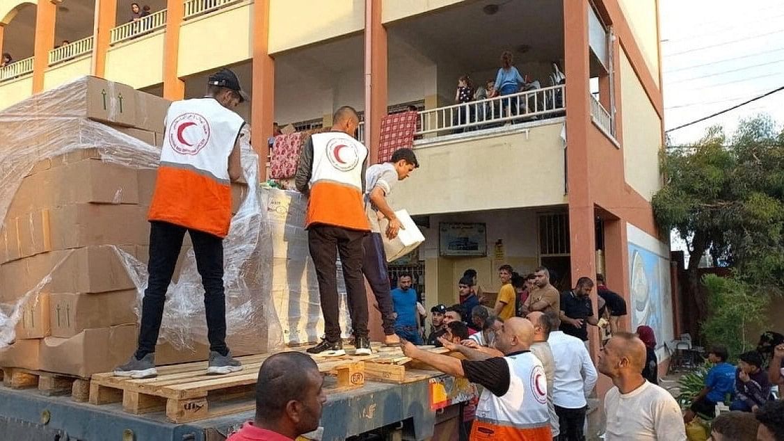 <div class="paragraphs"><p>Members of the Palestine Red Crescent Society distribute aid to people in Deir al-Balah, in the central Gaza Strip.&nbsp;</p></div>