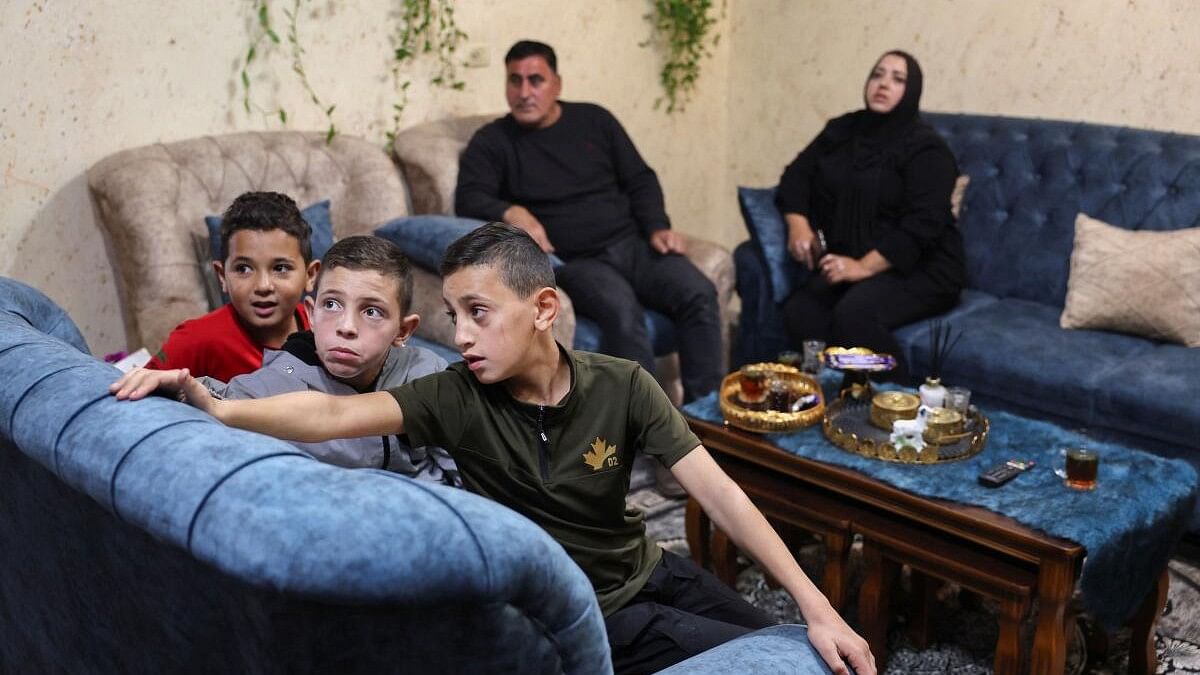 <div class="paragraphs"><p>The family of a young Palestinian prisoner watches on a television the news updates on the Israeli hostages and Palestinian prisoners swap deal, near Hebron.</p></div>