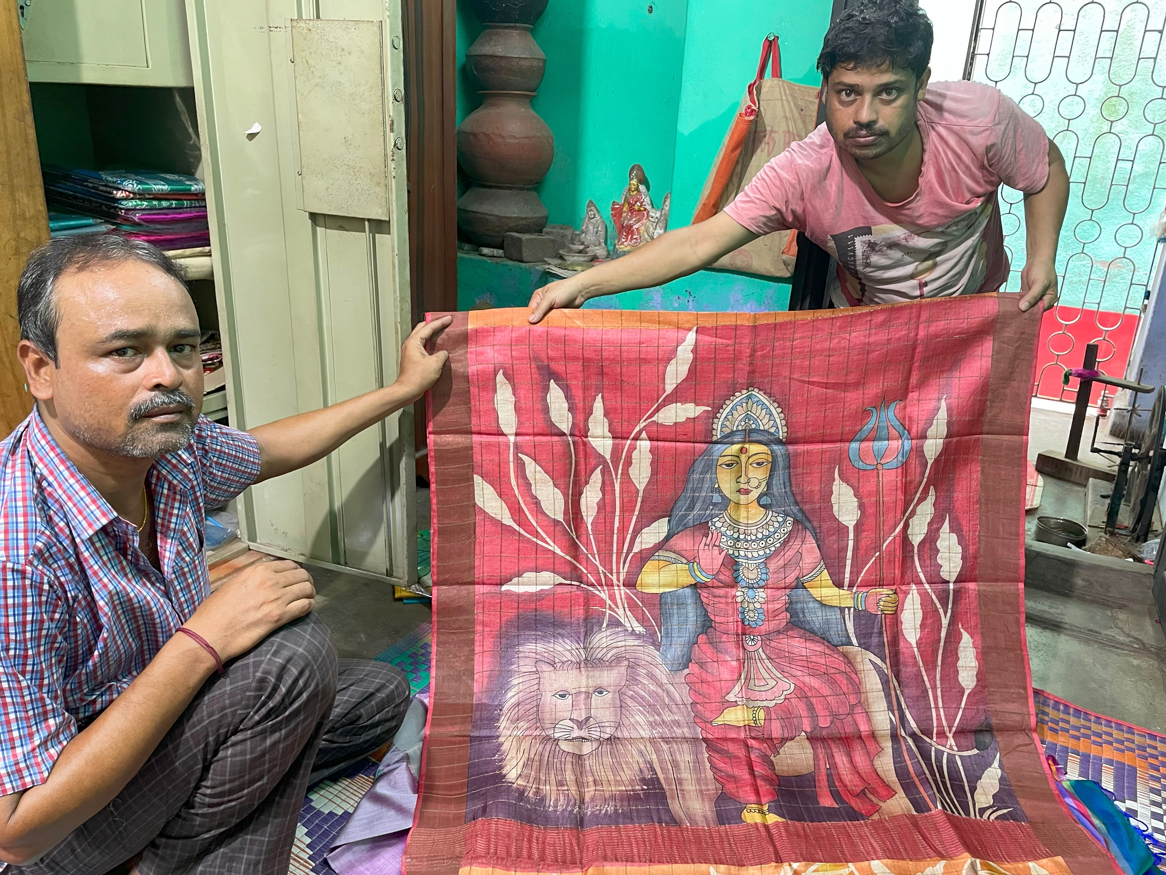 Mukul Khan (left) and an associate holding a Bishnupuri silk sari with Durga handpainted on it. 